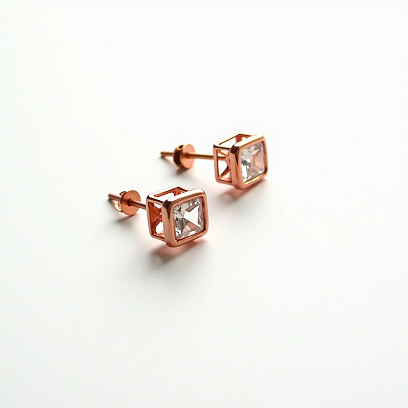 These moissanite earrings feature a square-cut moissanite stone set in a rose gold metal framework, highlighting a modern, geometric design. The stones are securely held within a prong setting, allowing light to pass through and enhance their brilliance. These earrings utilize a classic post and butterfly clasp attachment, ensuring a secure and comfortable fit when worn. The rose gold setting adds a warm, elegant touch, complementing the clear, sparkling moissanite stones beautifully.