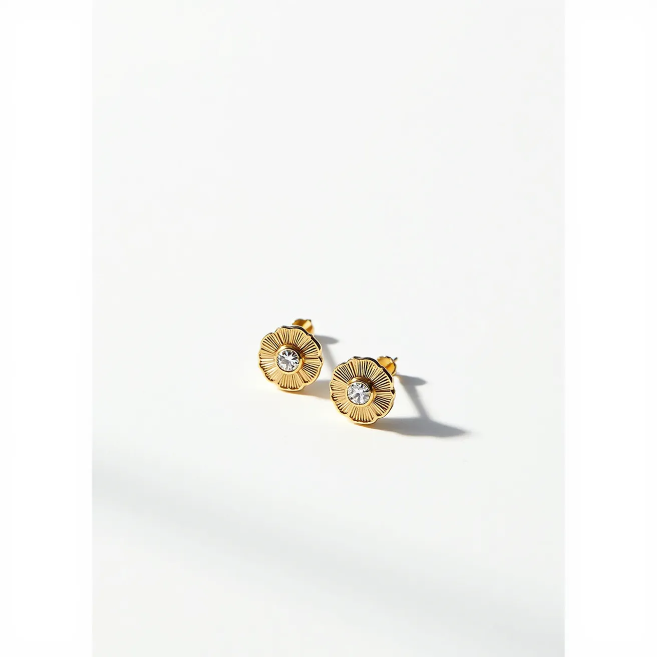 These moissanite earrings feature a beautiful gold-toned setting designed to resemble delicate flowers. At the center of each earring is a round, brilliant-cut moissanite stone that sparkles with clarity and precision. The petals surrounding the moissanite have a textured, radiating pattern, adding a luxurious touch. These earrings have a classic stud style with a secure post and butterfly clasp, making them both elegant and easy to wear.