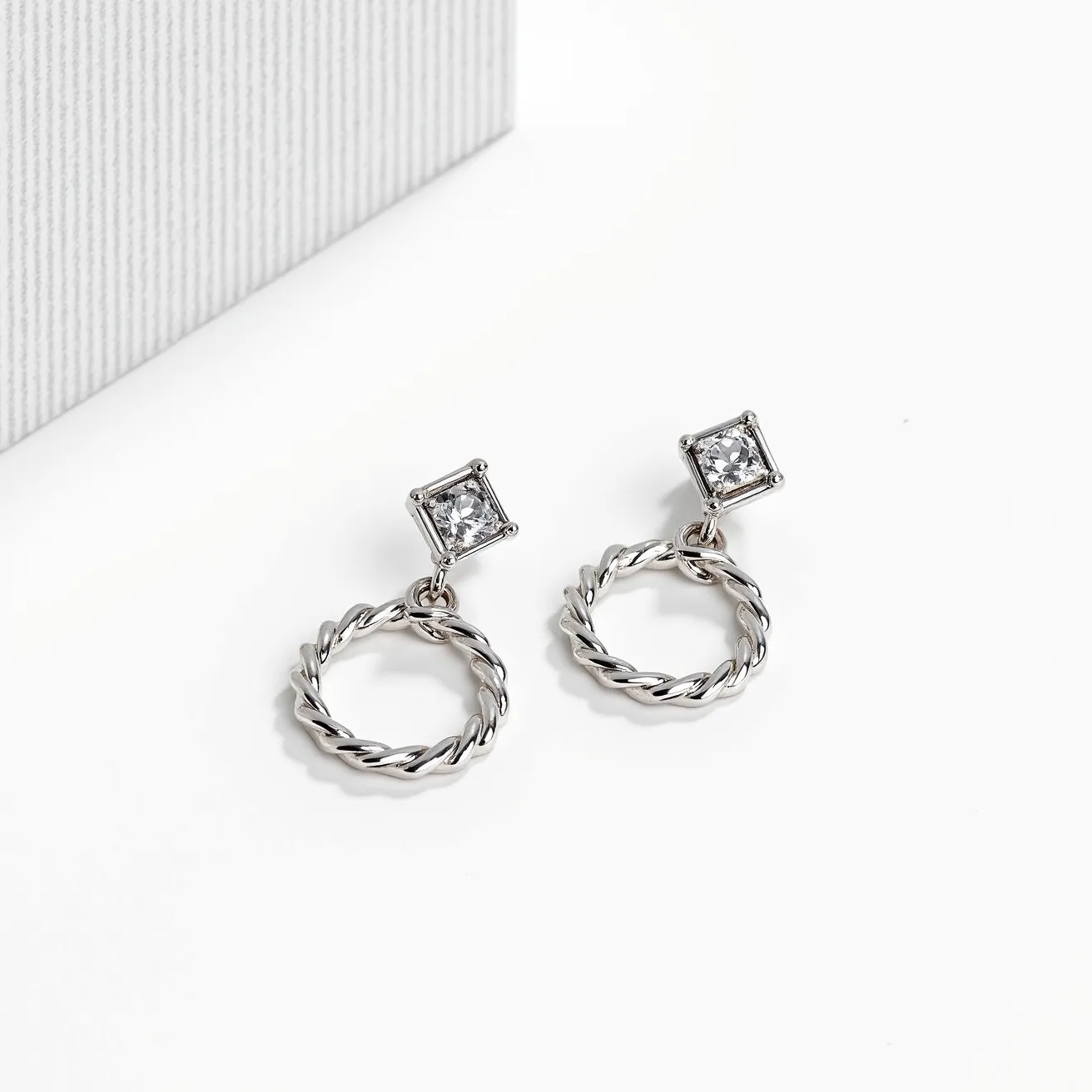 These moissanite earrings feature a dazzling square-cut moissanite gemstone set in a sturdy prong setting, which gives it a classic and elegant appearance. The earrings are crafted from a lustrous metal, possibly sterling silver or white gold, that enhances the brilliance of the moissanite. The design includes a twisted hoop drop, providing a distinctive and stylish element to the piece. The earrings are likely equipped with a secure post-back or push-back clasp, ensuring they stay comfortably in place when worn.