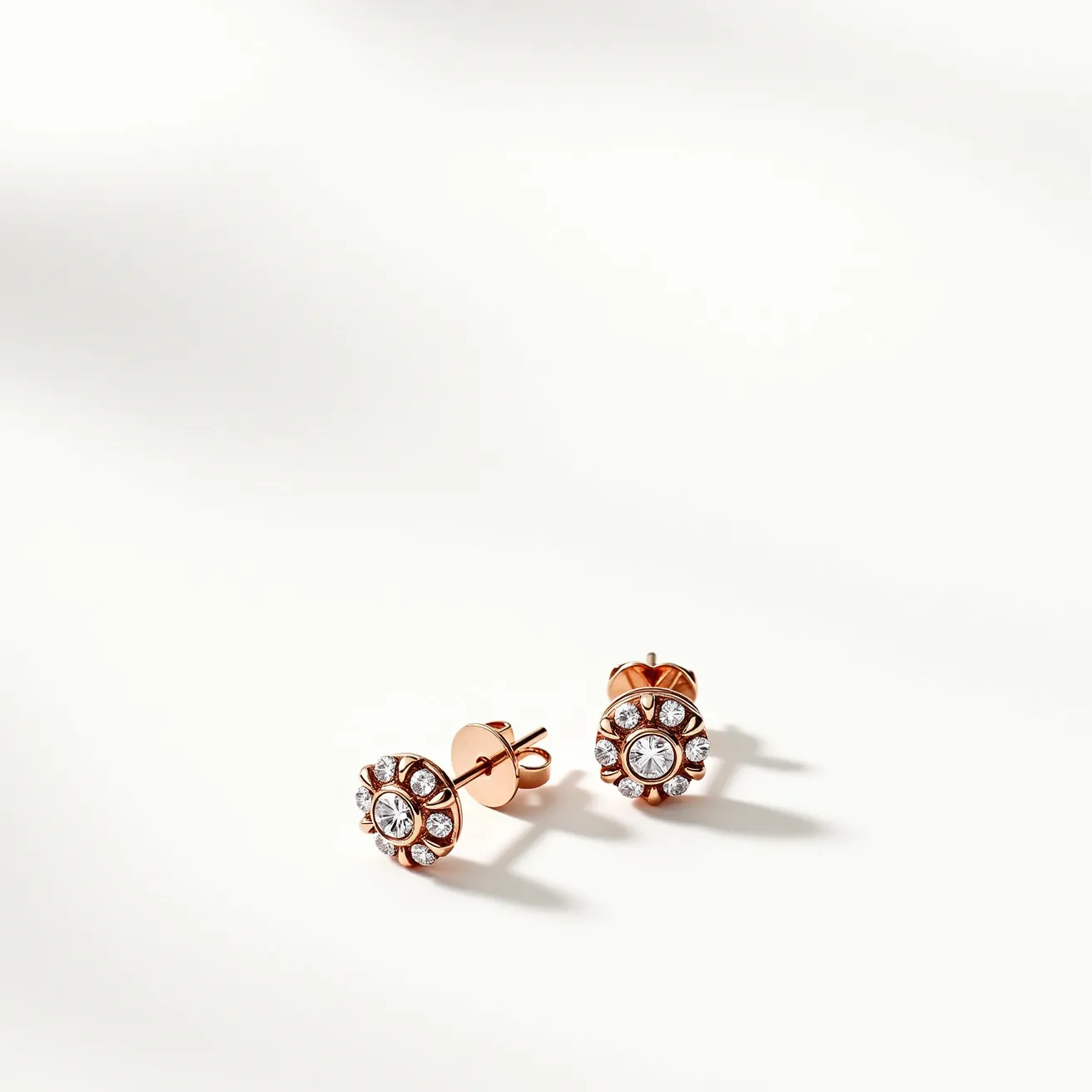 These moissanite earrings feature a central, round-cut moissanite set in a rose gold setting, surrounded by smaller moissanite stones arranged in a halo design. The earrings are crafted with a stud style and are secured with a classic push-back clasp, ensuring both elegance and functionality. The combination of the sparkling moissanite and the warm tone of the rose gold creates a sophisticated and timeless aesthetic.