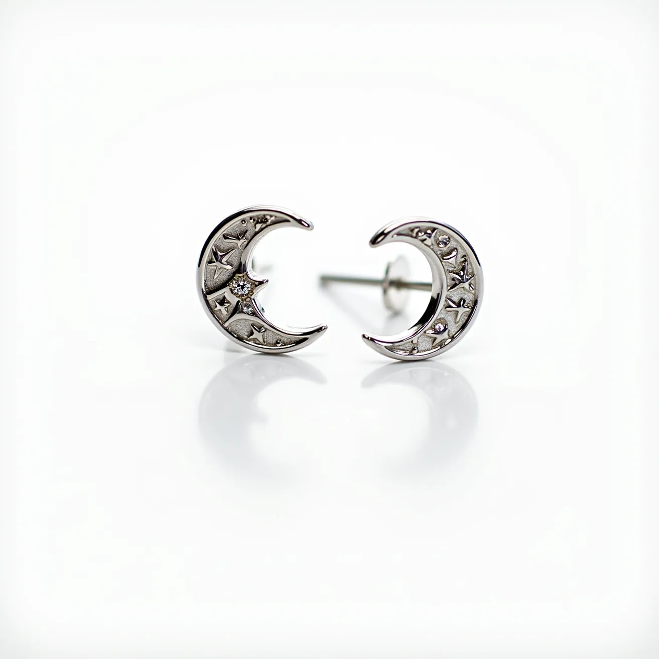 These moon earrings feature a polished silver-toned metal shaped into delicate crescent designs adorned with intricate star engravings. Each earring is embellished with a small, round-cut stone, likely to be a diamond or cubic zirconia, nestled within a star-shaped setting that enhances the celestial theme. The earrings are equipped with a classic post and butterfly clutch attachment, ensuring a secure fit while worn. The combination of metallic sheen and sparkling stones adds a touch of elegance and whimsy to these celestial-inspired accessories.