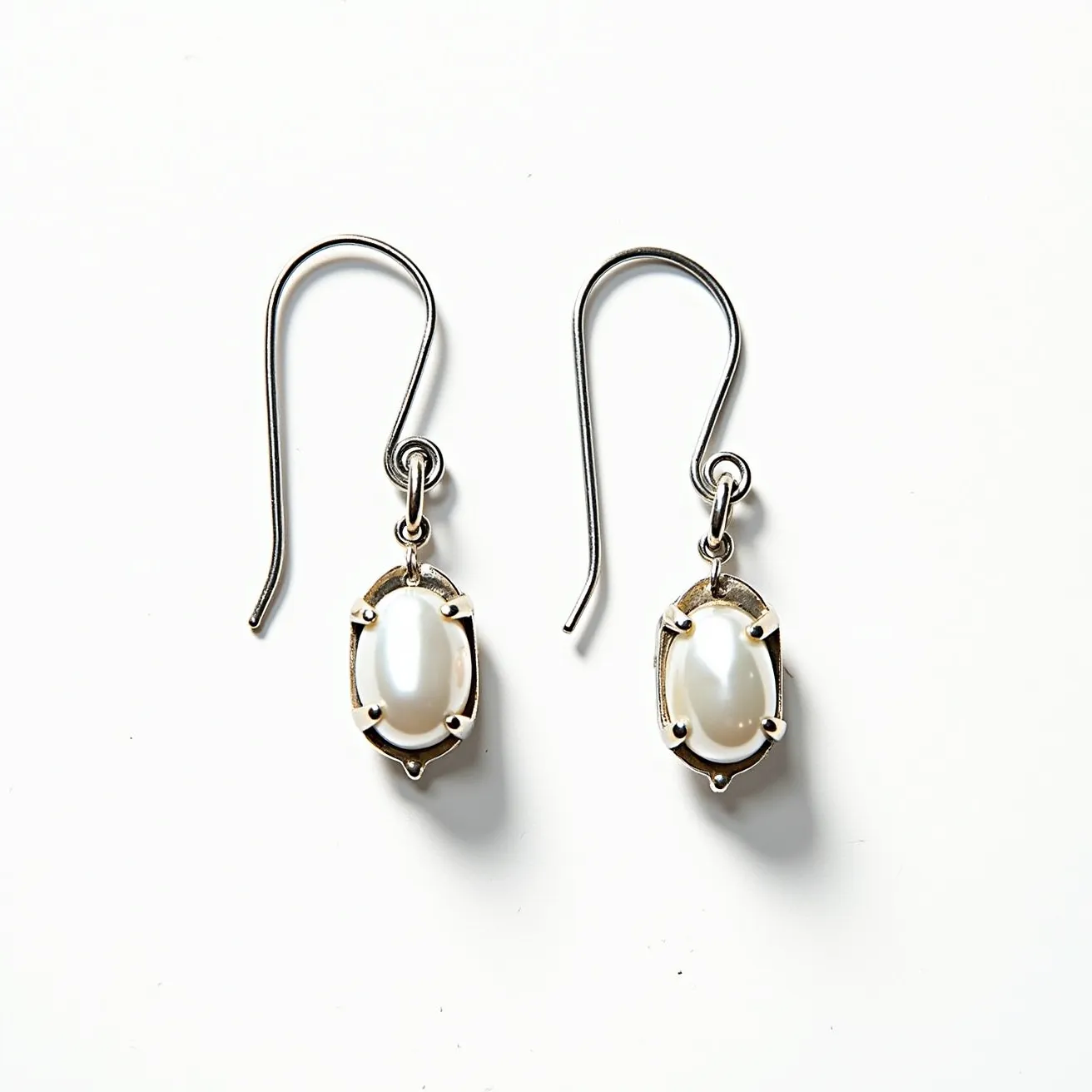 These pearl drop earrings feature lustrous pearls as the central element, set in a classic and elegant prong setting that securely holds each pearl in place. The pearls are smooth and oval-shaped, highlighting their natural sheen. The metal used appears to be a silver-toned metal, complementing the pure and sophisticated look of the pearls. The earrings use a simple hook clasp for easy wearing and removal, providing a sleek and unobtrusive attachment to the ear. The overall design is refined, allowing the beauty of the pearls to stand out.