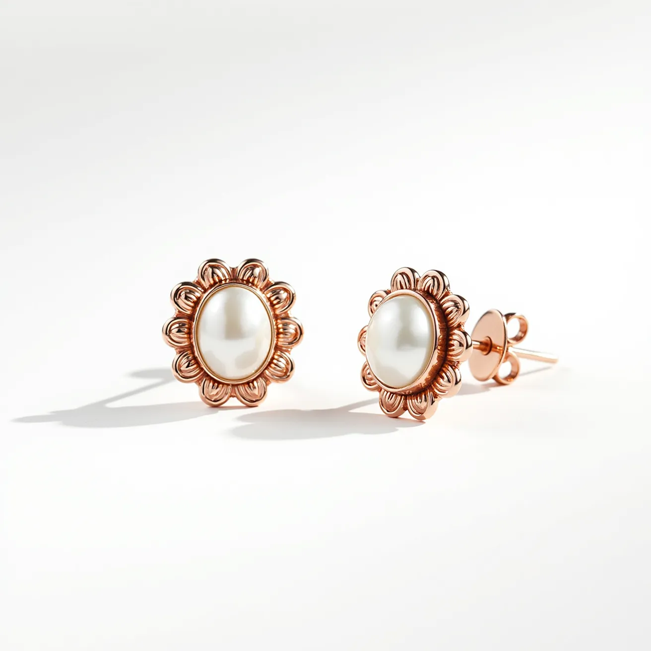 These pearl earrings feature a central, oval-shaped pearl set in a beautifully crafted metallic flower-like design. The metal appears to be rose gold, adding a warm and sophisticated tone to the piece. The scalloped floral setting complements the pearl, enhancing its elegance. These earrings are equipped with a post and butterfly back clasp, ensuring a secure fit. The combination of the pearl's smooth luster and the intricate floral detailing creates a harmonious and stylish accessory.