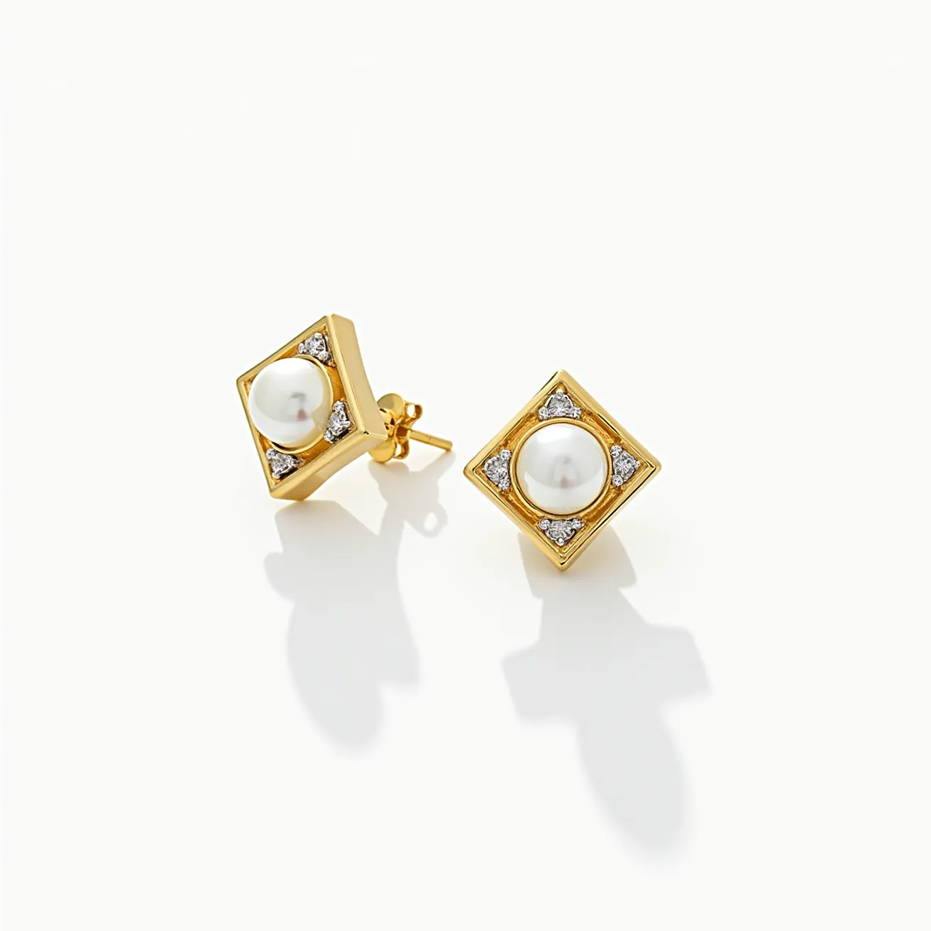 These pearl stud earrings feature a sophisticated design with a central, lustrous pearl set in a square gold frame. The frame is adorned with small, sparkling gems, likely diamonds, set at each corner, adding a touch of elegance and contrast to the smooth pearl. The earrings use a post and butterfly back clasp for secure attachment, ensuring they stay comfortably in place when worn. The combination of materials and craftsmanship creates a timeless and elegant accessory suitable for various occasions.