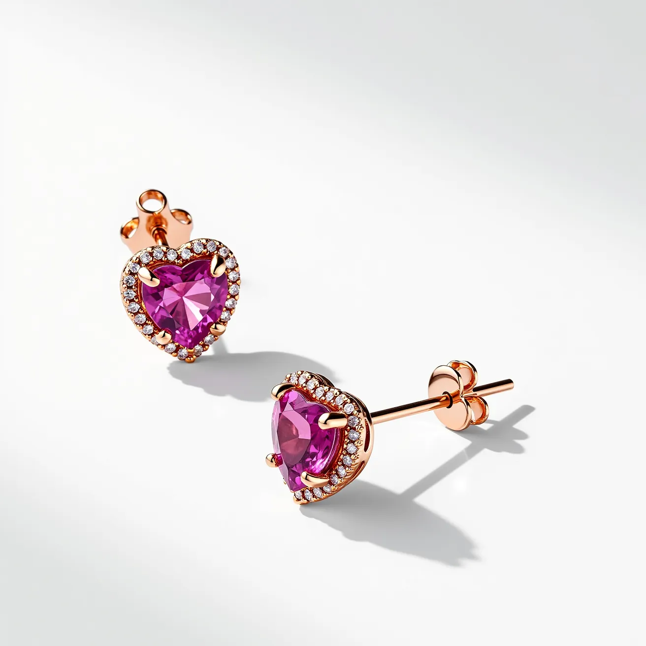 These pink earrings feature heart-shaped stones with a vibrant pink hue, set in a delicate rose gold setting. Surrounding the central gem is a halo of small, round-cut clear stones that add a touch of brilliance and contrast. Each earring is secured with a butterfly clasp, ensuring a snug and comfortable fit. The heart-shaped stones are held in place with prongs that match the rose gold setting, creating a cohesive and elegant design.