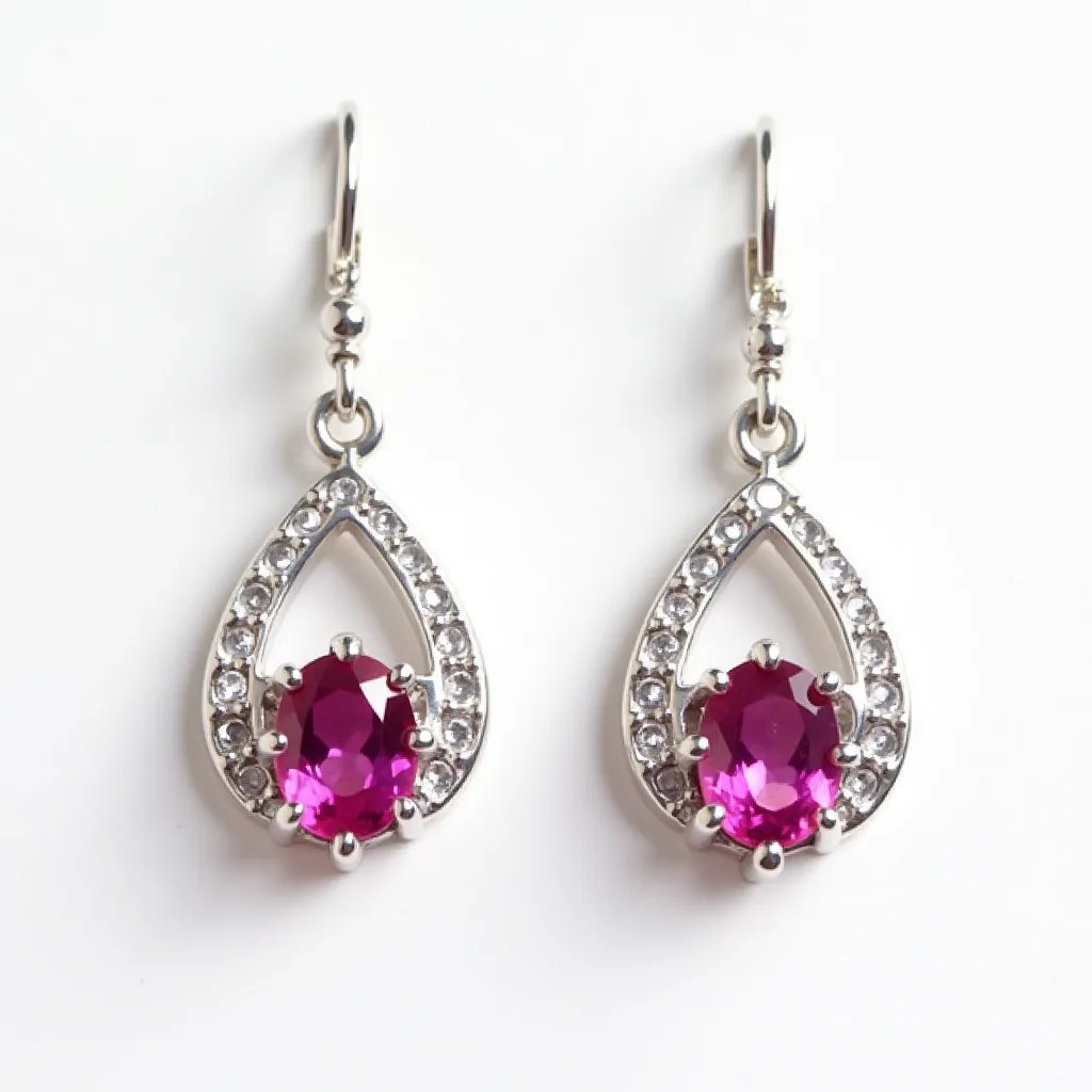 These pink earrings feature a teardrop design crafted from a silver-toned metal, adorned with a series of small, clear stones set in a pavé style along the curve of each earring. At the center of the design is a vivid pink oval gem, likely a faceted stone, held securely in place with a prong setting that highlights its brilliance and color. The earrings are equipped with a hook clasp, providing a simple yet secure attachment mechanism that complements their elegant design.