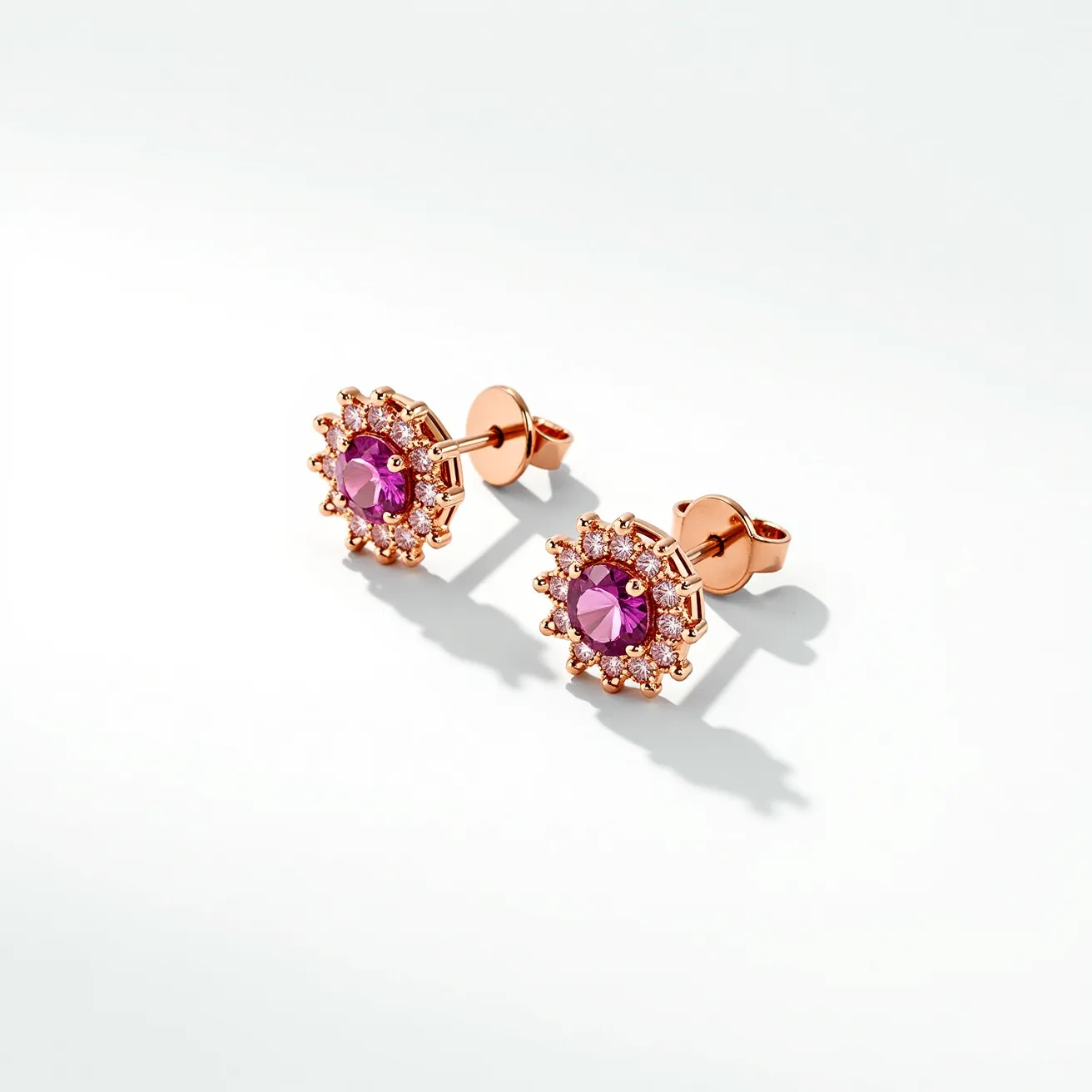 These pink sapphire earrings feature a central pink sapphire gemstone, showcasing a round cut that enhances its brilliance and vibrant hue. The sapphire is encircled by a halo of small, round-cut diamonds, adding a touch of sparkle and elegance to the design. The gemstones are set in a metal that appears to be rose gold, complementing the pink tones of the sapphire. The earrings use a post and butterfly clutch back, providing a secure yet easy-to-use attachment. The overall design exudes a classic yet modern aesthetic, with careful attention to detail in the setting and choice of materials.