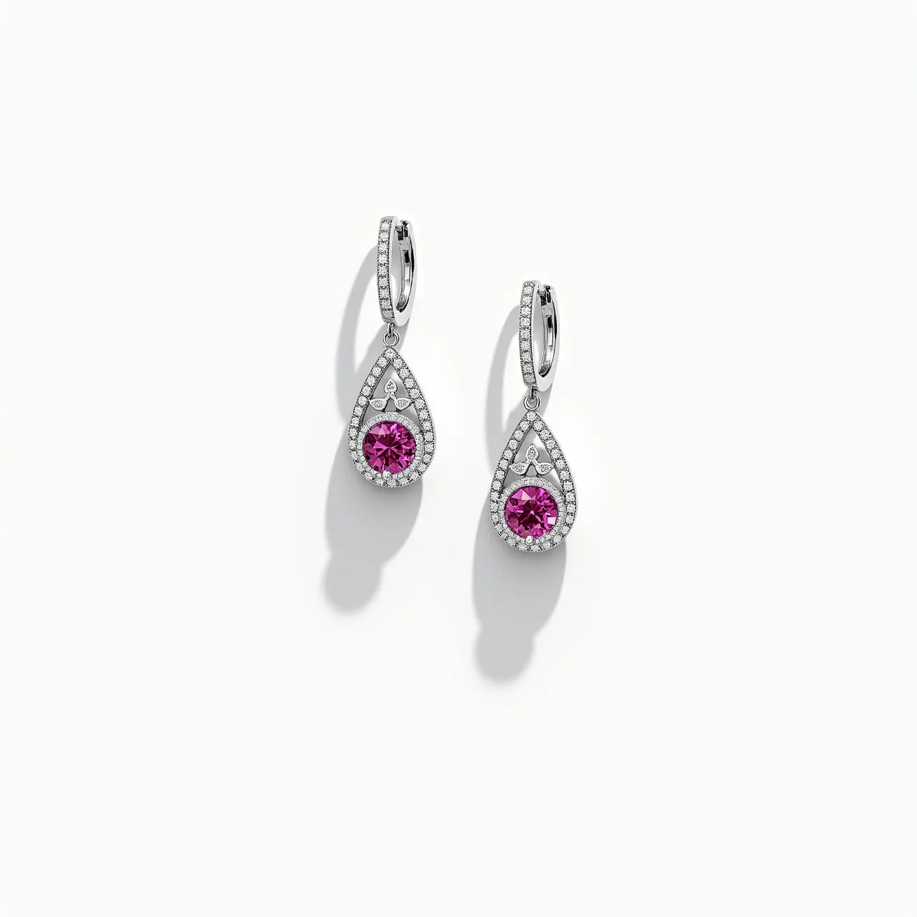 These pink sapphire earrings feature a stunning teardrop design, with each earring showcasing a vibrant, round-cut pink sapphire at the center. The sapphires are surrounded by a halo of small, sparkling diamonds, accentuating their brilliant color and enhancing the overall glamour of the piece. The teardrop-shaped setting is crafted from a polished metal, likely white gold or platinum, which complements the cool tones of the diamonds and offers a secure and elegant framework for the stones. The earrings are attached with hinged leverback clasps, providing both security and comfort for the wearer. These elements come together to create a sophisticated and timeless accessory.