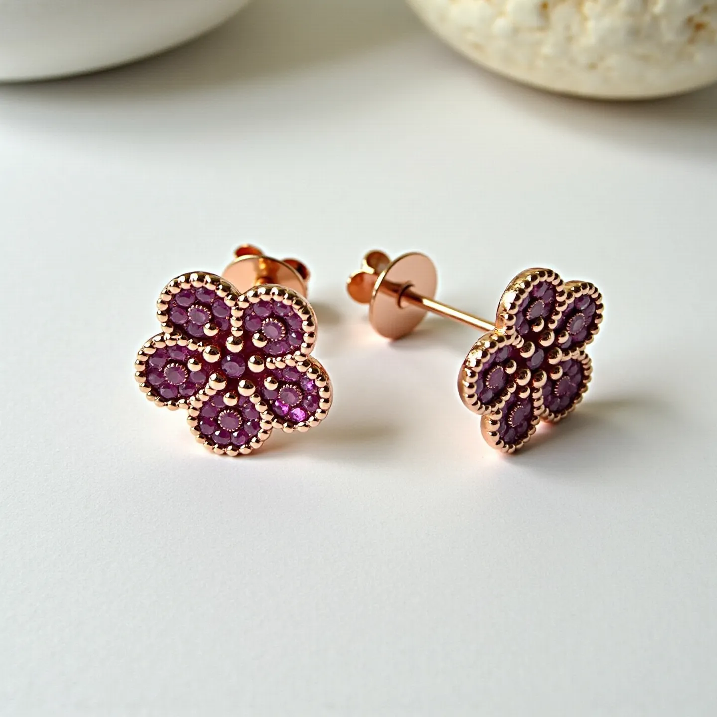 These pink sapphire earrings feature a floral design, with multiple round-cut pink sapphires arranged in a layered petal formation. Each earring consists of five distinct petals, each centered with a slightly larger sapphire, surrounded by finely detailed bead-like metalwork that enhances the overall elegance. The metal appears to be rose gold, complementing the vibrant tone of the sapphires and adding a touch of warmth. The earrings have a classic post and butterfly clasp attachment, ensuring secure wear while maintaining the delicate aesthetic.