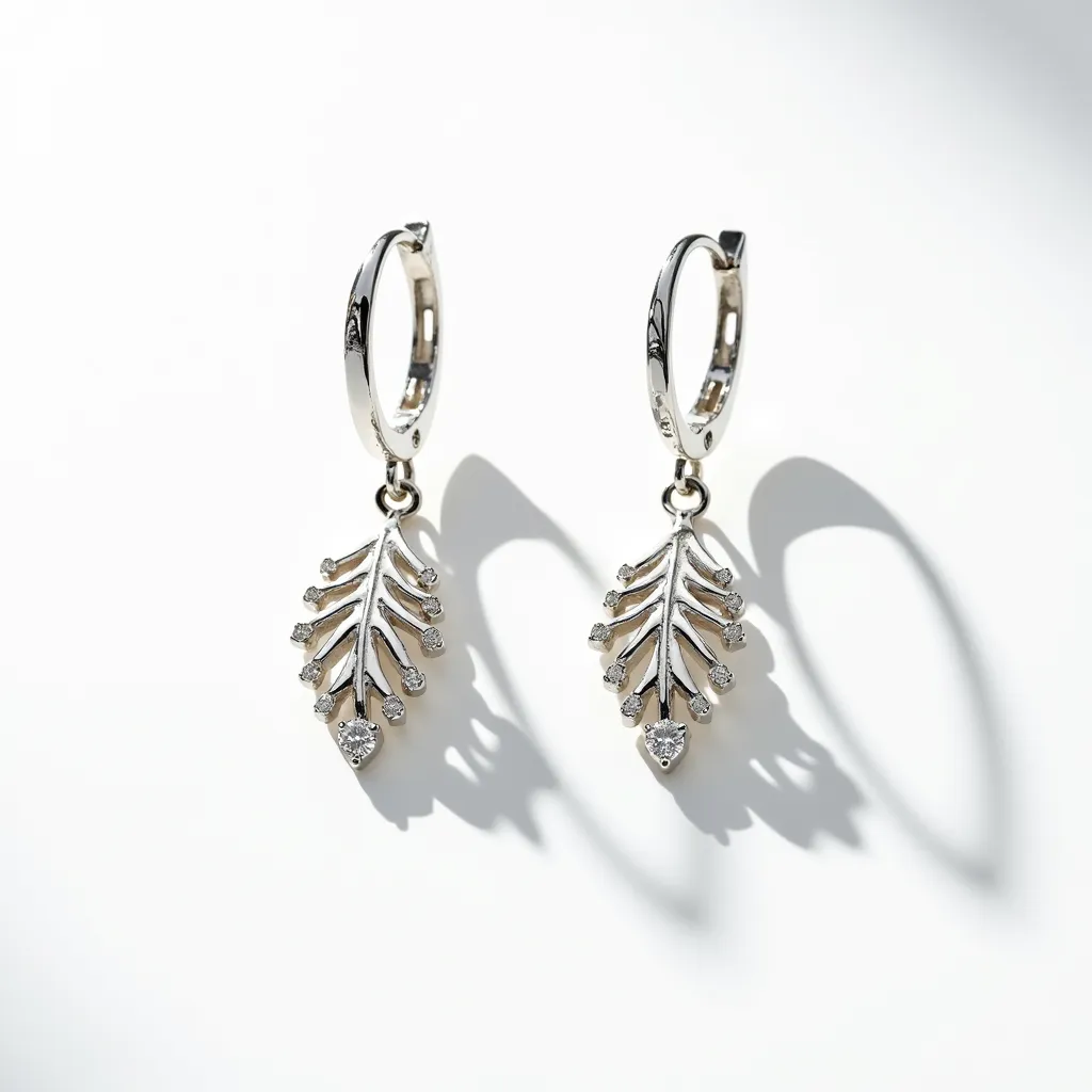 These silver dangle earrings feature an elegant leaf design, crafted from a shiny silver material. Each earring is adorned with small, round-cut gemstones strategically placed along the veins of the leaf, adding a subtle sparkle. The earrings are attached to thin, silver hoop clasps that are polished to a smooth finish, allowing for a secure and comfortable fit. The intricate detailing of the leaf design showcases a sophisticated craftsmanship, making these earrings a stylish accessory for various occasions.