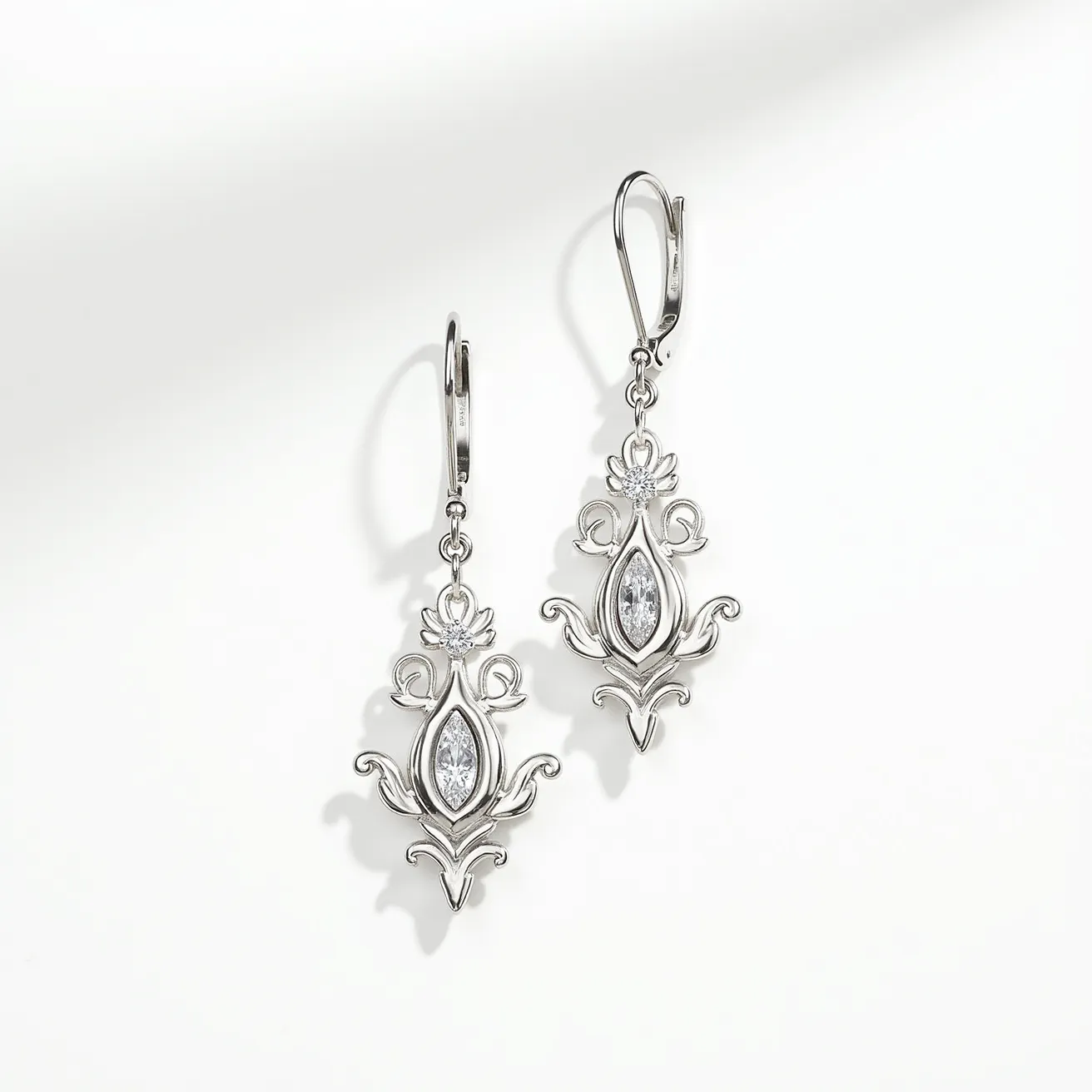 These silver drop earrings feature an intricate design crafted from high-quality silver. At the center of each earring is a marquise-cut gem, set securely within an elegant and ornate silver framework. The gemstones appear clear and faceted, catching light to enhance their brilliance. The earrings are suspended from a lever-back clasp, providing both security and ease of wear. The overall aesthetic is both classic and sophisticated, making them suitable for a variety of occasions.