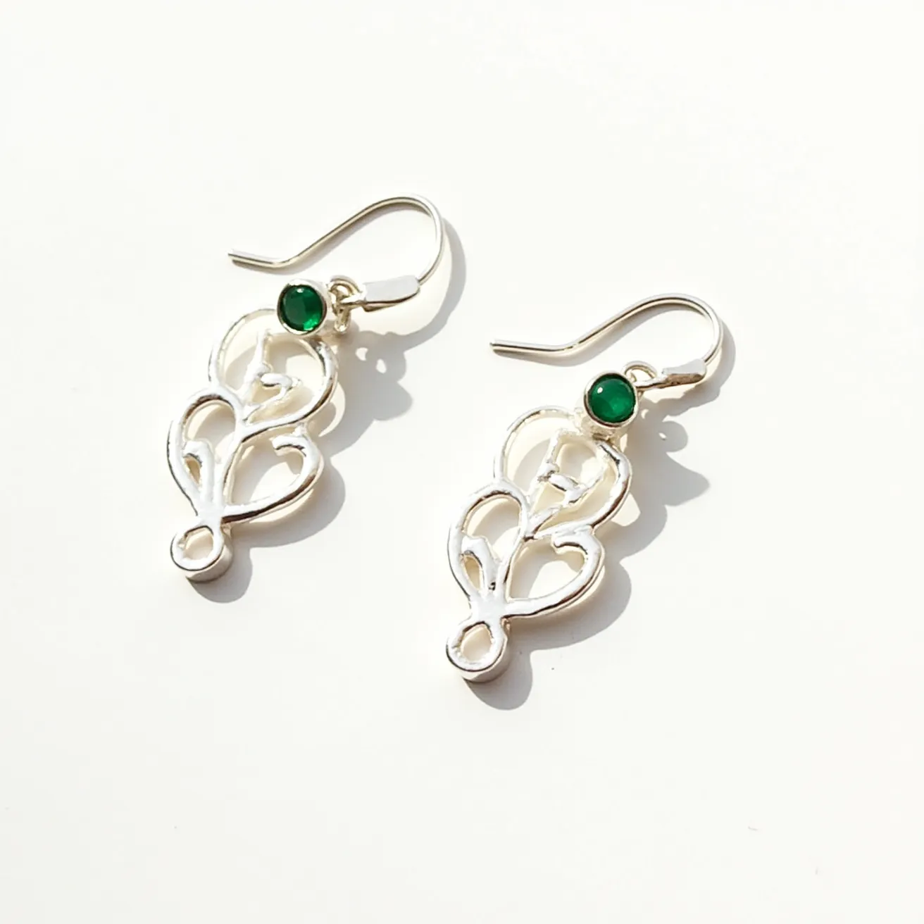 These silver earrings feature an elegant openwork design, crafted from sterling silver, with a focus on delicate curves and loops. At the top of each earring is a small round green gem, likely an emerald or a similar stone, set in a bezel setting that highlights its deep color. These earrings use a hook attachment, offering ease of wear. The combination of silver and green adds a touch of sophistication and classic beauty to the piece.