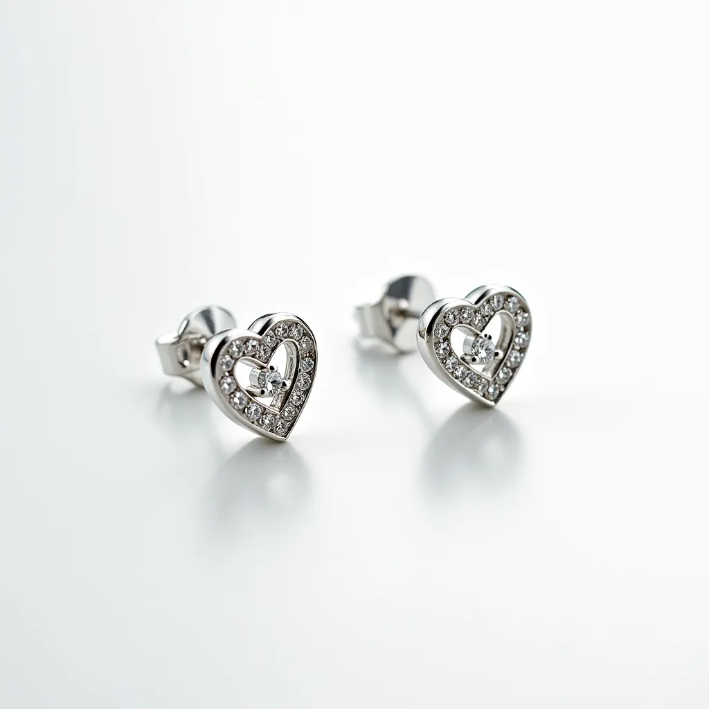 These silver heart earrings feature an elegant design with a polished silver setting in the shape of a heart. The front of each earring is adorned with small, round-cut clear stones, likely cubic zirconia or diamonds, which are pave-set to enhance their sparkle and elegance. In the center of the heart, there is a larger round-cut stone set in a prong setting, adding a focal point that draws attention. The earrings are designed with a post back and butterfly clasp attachment, ensuring a secure and comfortable fit on the earlobe.