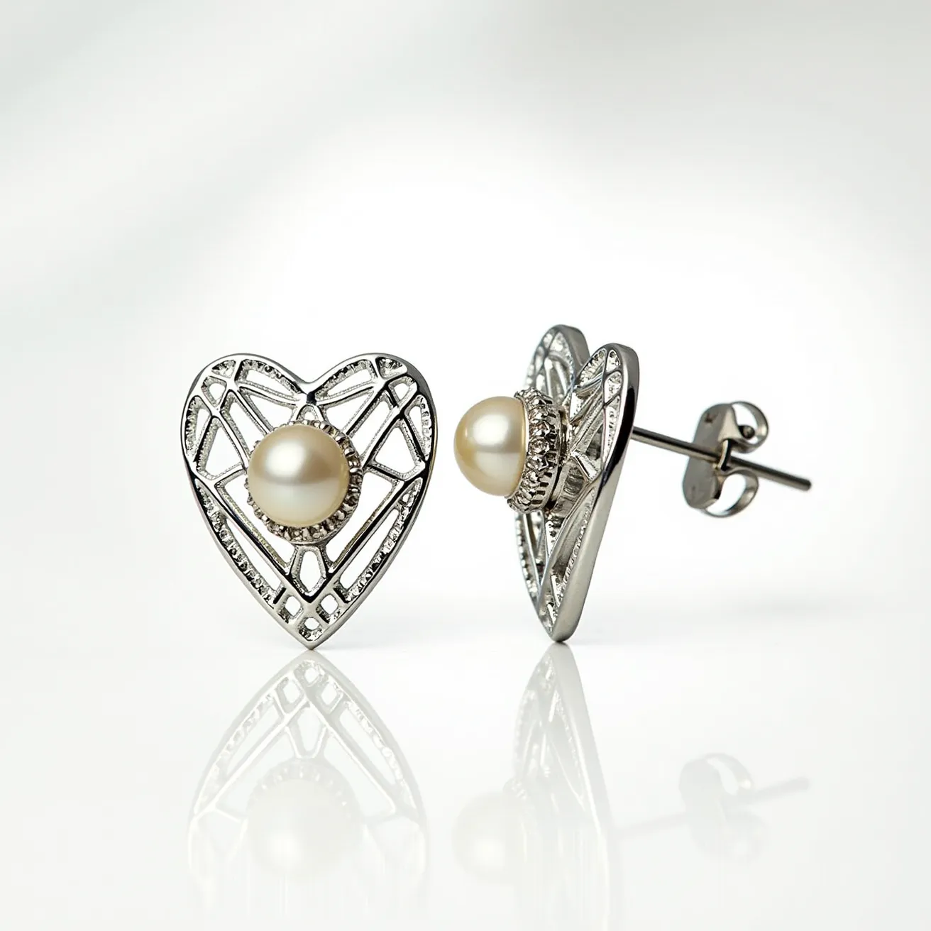 These silver heart earrings feature an elegant openwork design crafted from polished silver. At their center, each earring showcases a lustrous white pearl, inset with a decorative bezel setting that enhances the classic appeal. The earrings are designed with a stud attachment, secured with a butterfly clasp, ensuring both comfort and security when worn. The combination of the metallic heart framework and the smooth round pearls creates a timeless and versatile piece, ideal for a variety of occasions.