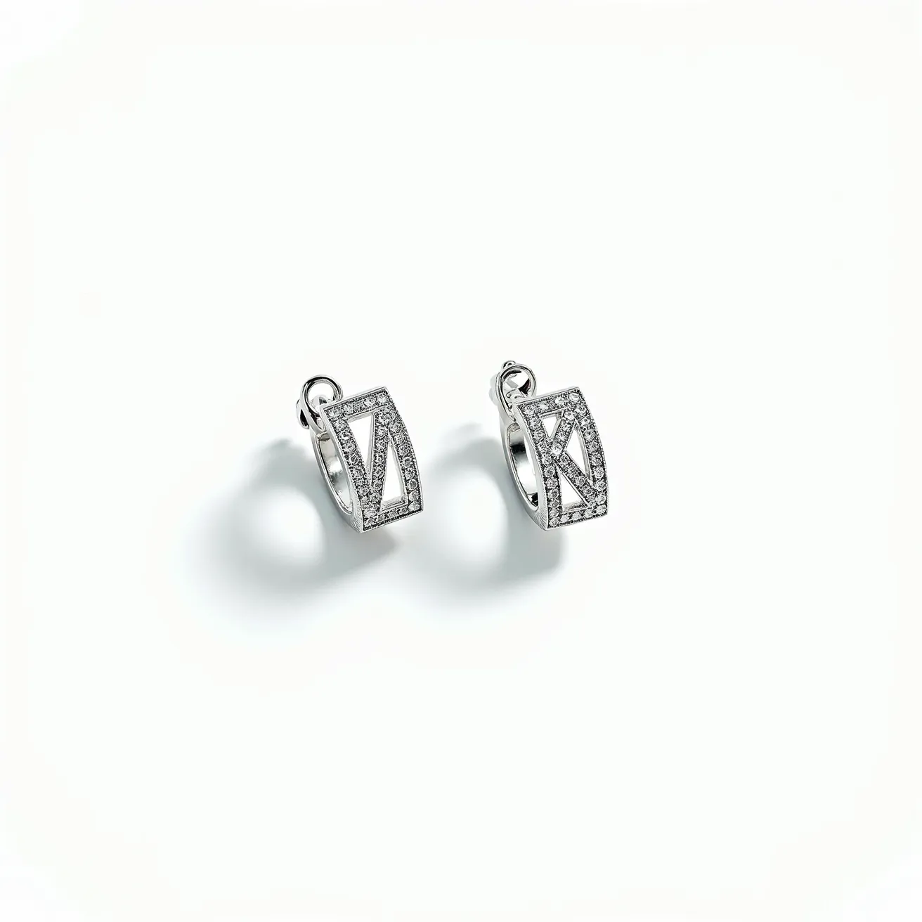 These silver huggie earrings feature a sleek, modern design crafted from sterling silver. They are adorned with small, sparkling stones that appear to be diamonds or diamond-like in a pavé setting, adding a touch of elegance and shine. The stones are meticulously set within a rectangular frame that creates an intriguing geometric pattern. The earrings are equipped with a convenient huggie clasp, ensuring a secure fit around the earlobe while maintaining a comfortable and stylish appearance.