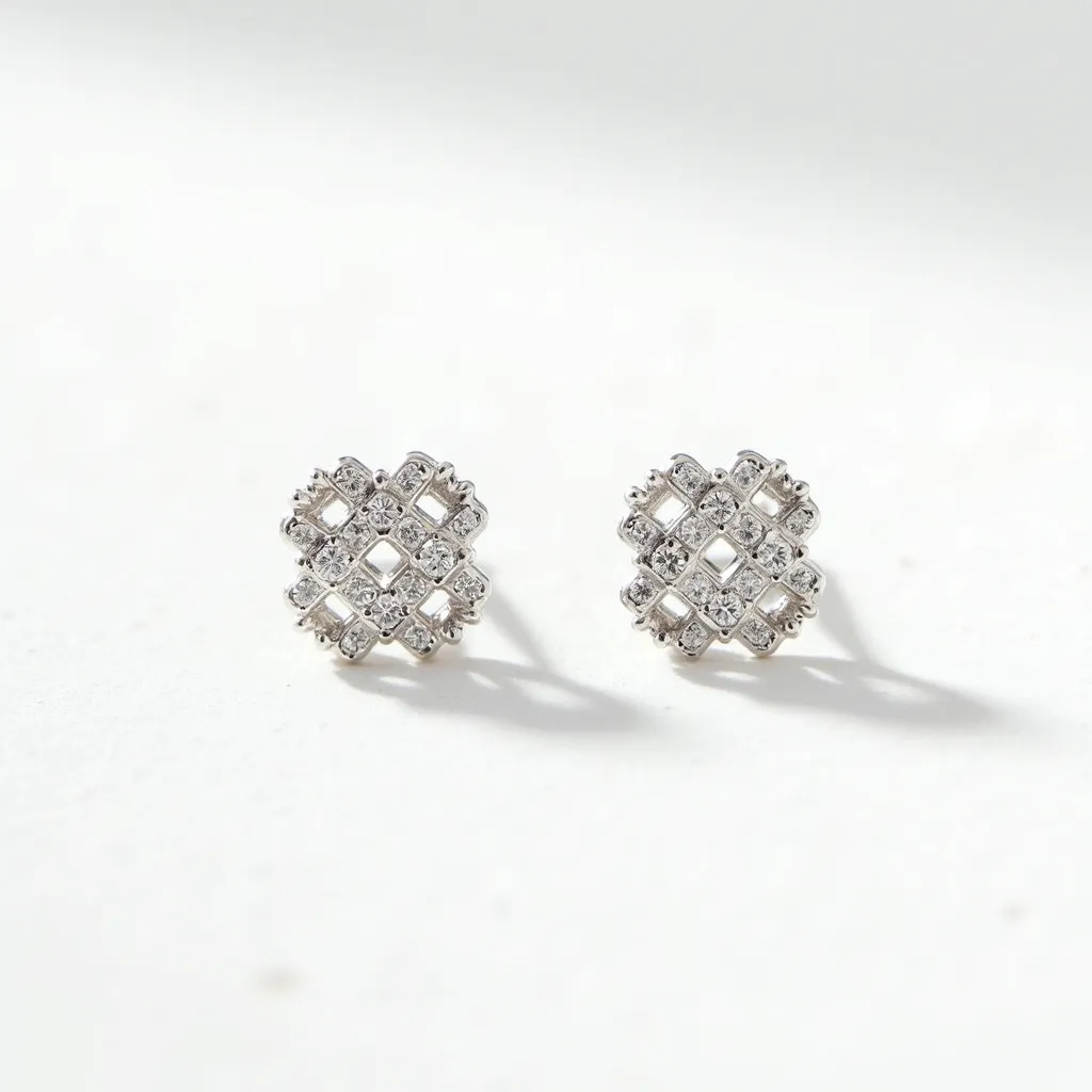 These silver stud earrings display a sophisticated lattice pattern, enhanced by an array of small, clear gemstones that are likely round-cut. Each stone is set securely, complementing the intricate design with brilliance. The setting highlights the stones while maintaining the earrings' elegant silver framework. The attachment mechanism appears to be a traditional post, typical for stud earrings, ensuring a secure and comfortable fit. The overall craftsmanship highlights a balanced combination of sparkle and refined detail.