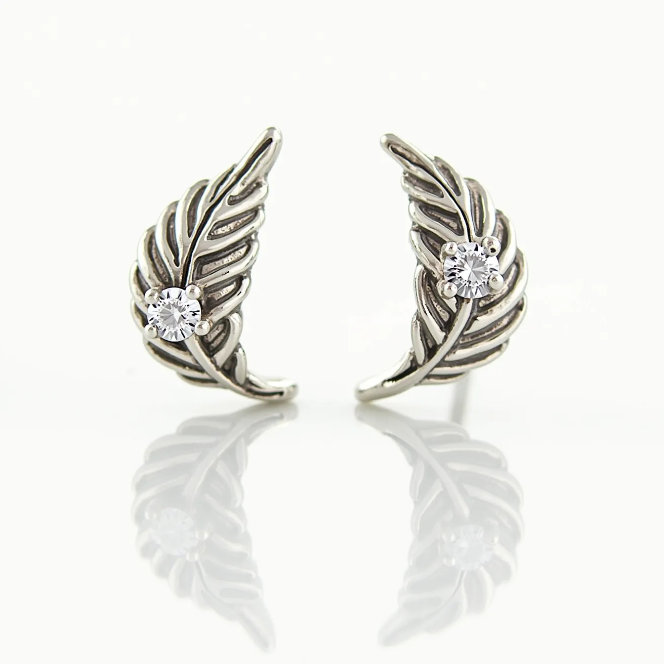 These silver stud earrings feature an intricate leaf design crafted from silver, with each earring highlighting a small, round-cut gem at its center. The gem is set in a classic four-prong setting, which securely holds the stone while allowing ample light to enhance its sparkle. The earrings are likely attached with standard posts, typical for stud earrings, providing a simple yet elegant fastening suitable for everyday wear. The overall design combines elegance with a nature-inspired motif, making them a versatile accessory.