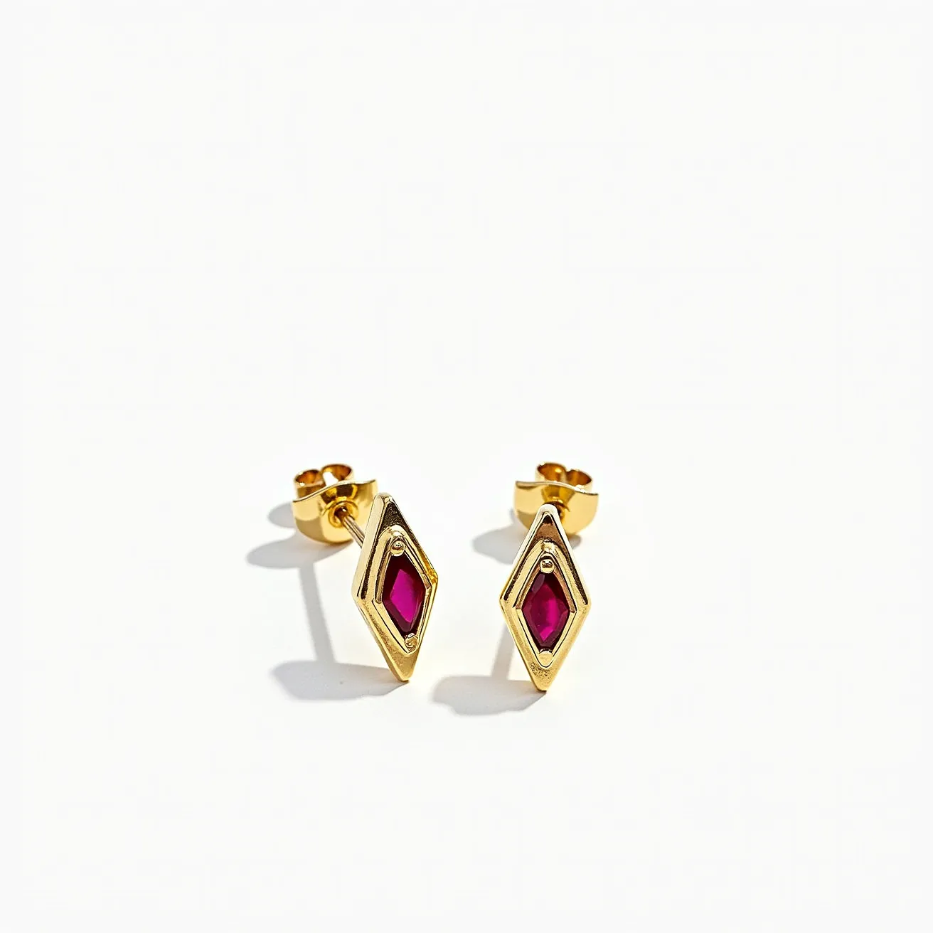 These small earrings feature a sleek geometric design, elegantly composed of a gold-toned metal. At the center of each earring is a marquise-cut gemstone with a deep red hue, likely a ruby or red garnet, set securely within a bezel setting that enhances its vibrant color. The earrings are finished with a simple and classic stud post and butterfly back clasp, ensuring both comfort and security for the wearer. The overall design combines modern elegance with a touch of classic sophistication, making them a versatile accessory for various occasions.