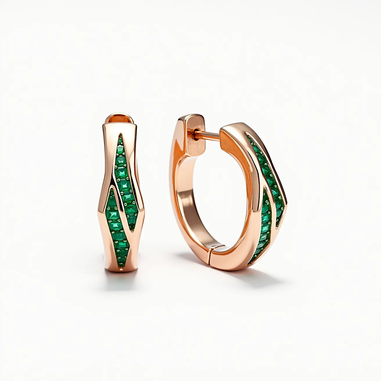 These small earrings are crafted from a rose gold material, forming a sleek, modern huggie hoop design. They are adorned with vibrant green stones, likely emeralds, intricately channel-set in a linear pattern along the outer edge of the hoop. The stones appear to be cut in a square shape, offering a geometric contrast to the fluid curves of the gold setting. The clasp mechanism features a hinged back that ensures secure attachment, blending seamlessly with the overall aesthetic of the piece.