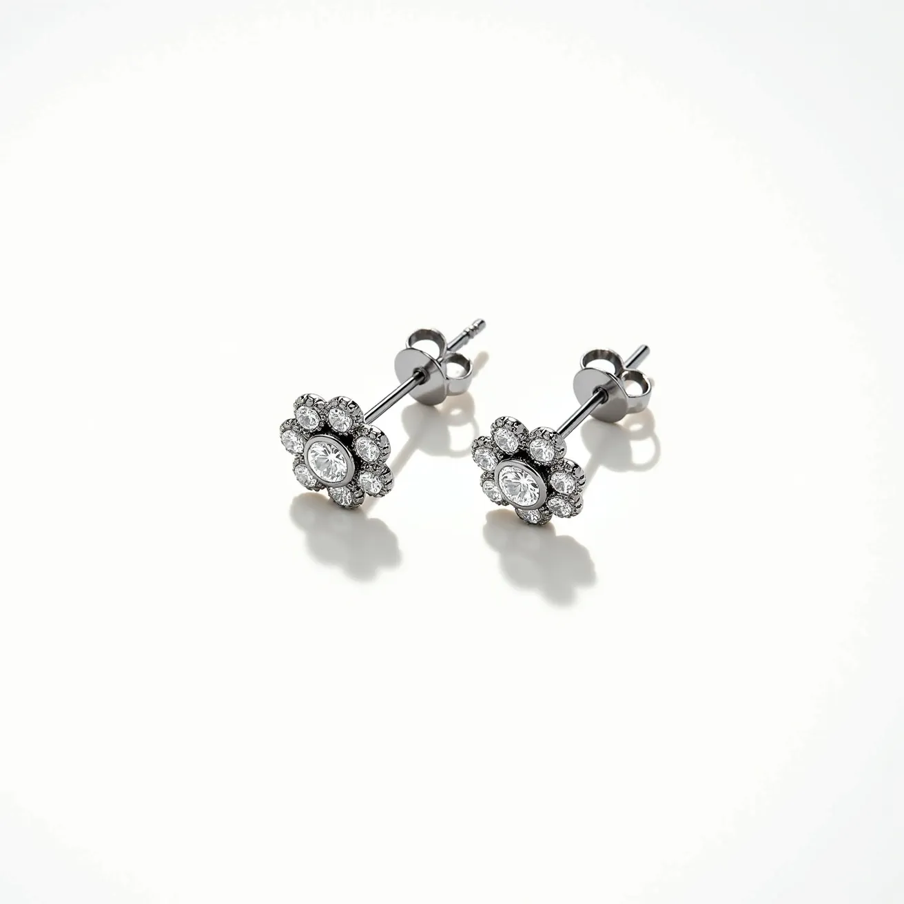 These small earrings feature a delicate floral design with a central round-cut gem that appears to be a diamond, surrounded by a halo of smaller round diamonds. The gemstones are likely set in a silvery metal, possibly white gold or platinum, enhancing the brilliance of the stones. The setting is a prong type, which securely holds each stone. The earrings have a post-back design with a butterfly clutch, ensuring they are easy to wear and secure. Their elegant design and fine materials suggest they are a suitable accessory for both everyday wear and special occasions.