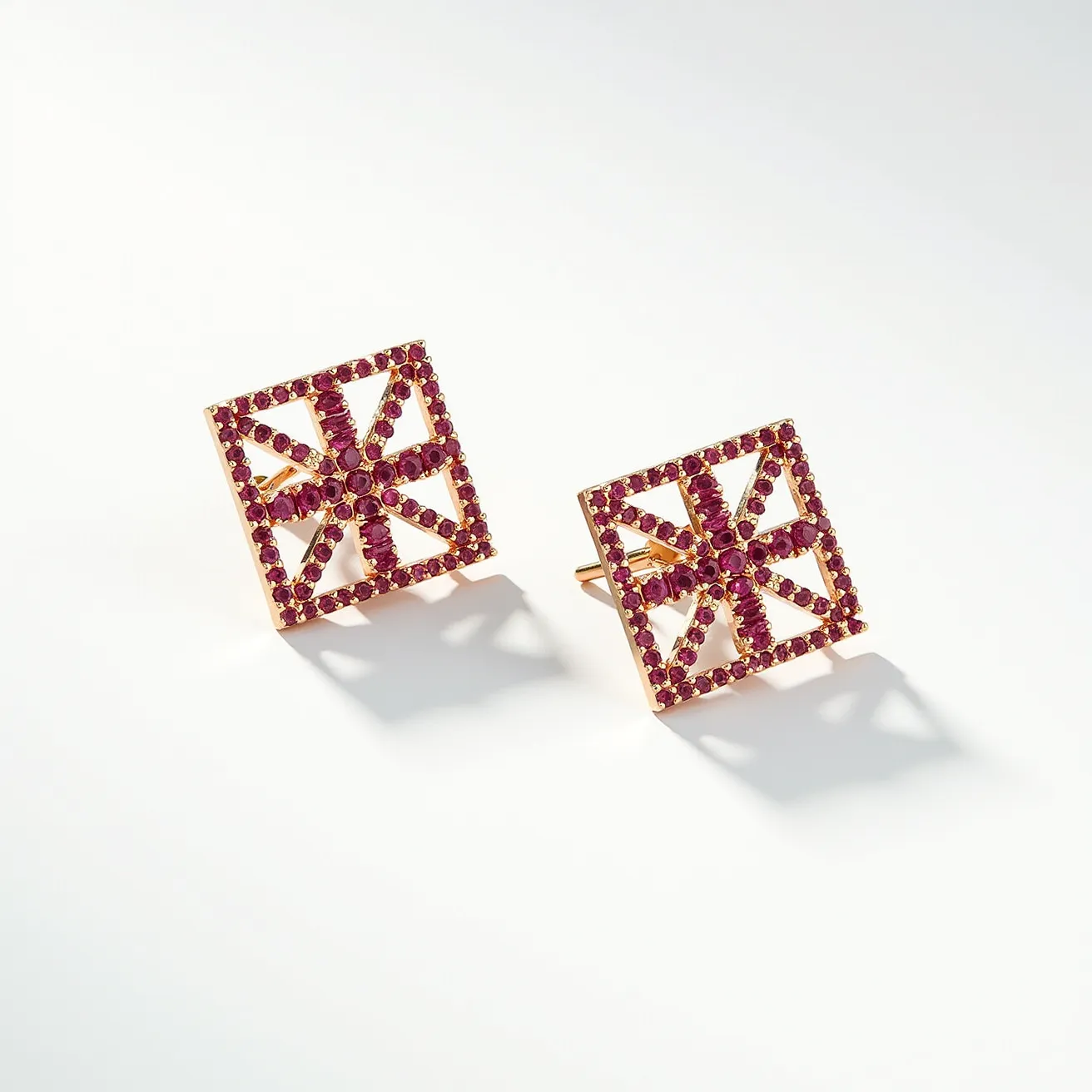 These square earrings feature a striking geometric design, encrusted with what appear to be small, round-cut red gemstones, possibly rubies, set in a lattice pattern. The stones are securely placed in a prong setting, enhancing their vibrant color and reflective quality. The earring structure is likely crafted from a gold-toned metal, providing a warm contrast to the red gemstones and offering durability. The earrings are designed with a post-back clasp, ensuring a secure and comfortable fit for wear. The meticulous arrangement of stones creates a visually appealing pattern that adds a touch of elegance and modernity to the overall design.