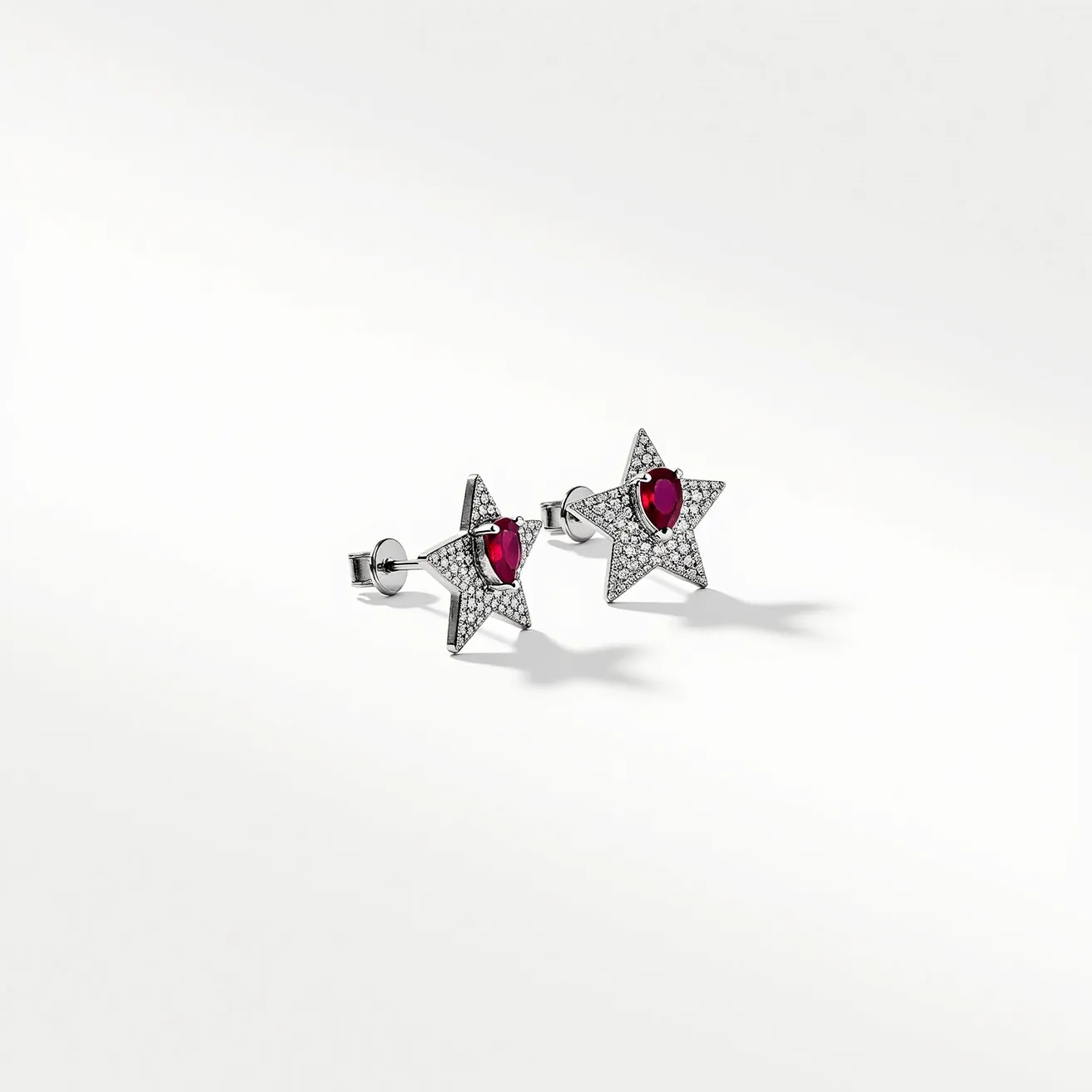 These star stud earrings are crafted with a sparkling design, featuring a star-shaped metal base adorned with small, presumably diamond-like stones that add a glittering appearance. At the center of each earring is a pear-cut red gemstone, possibly a ruby, which is set in a prong setting to highlight its vivid color. The earrings are equipped with a classic post and butterfly clasp, ensuring secure and comfortable wear. The combination of the bright central stone and the surrounding pave-style settings creates a striking and elegant aesthetic.