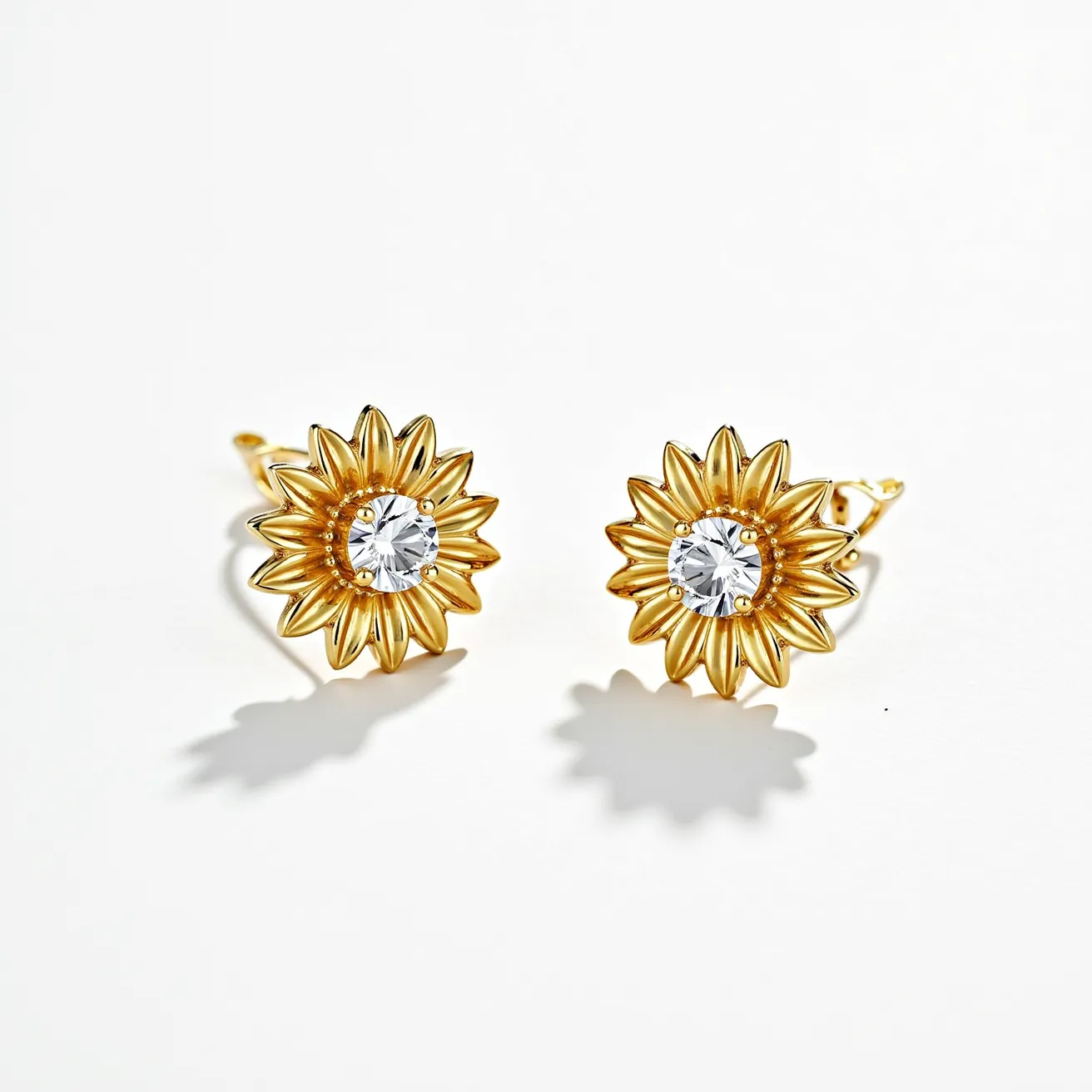 These sunflower earrings have a beautifully detailed floral design crafted from gold-toned metal, giving them a radiant and elegant appearance. At the center of each earring is a round-cut gem, possibly a clear stone like a diamond or a cubic zirconia, set in a prong setting that enhances its brilliance. The petals of the sunflower are intricately shaped, adding depth and texture to the overall design. These earrings are equipped with a classic post and butterfly clutch attachment, ensuring secure and comfortable wear. The combination of the gleaming petals and sparkling center stones creates a strikingly elegant and timeless accessory.