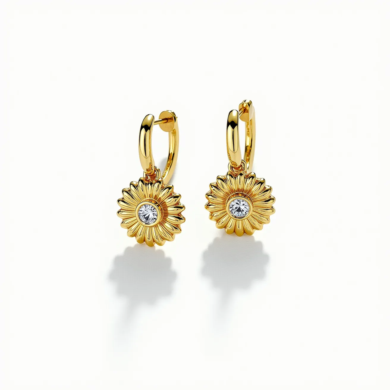 These sunflower earrings are crafted with a radiant gold finish, featuring a sunflower design with meticulously detailed petals. At the center of each flower, a round brilliant-cut gem is prominently set, likely a clear stone that resembles a diamond or crystal, mounted in a bezel setting. The earrings are designed with a secure hoop clasp that adds both elegance and functionality, making them easy to wear. The harmonious combination of the lustrous gold material and the central sparkling gem creates an eye-catching and sophisticated accessory.