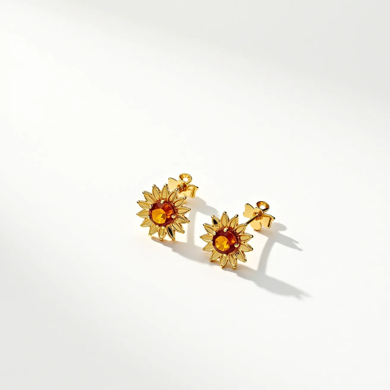 These sunflower earrings feature a radiant floral design crafted from a golden-hued metal, with each earring showcasing a vibrant, faceted orange gemstone at its center. The stones are round cut and set in a bezel setting, enhancing the sunflower motif by mimicking the flower's central disc. The petals are delicately formed, adding texture and dimension. The earrings are secured with a classic post and butterfly clutch back, ensuring they stay comfortably in place.