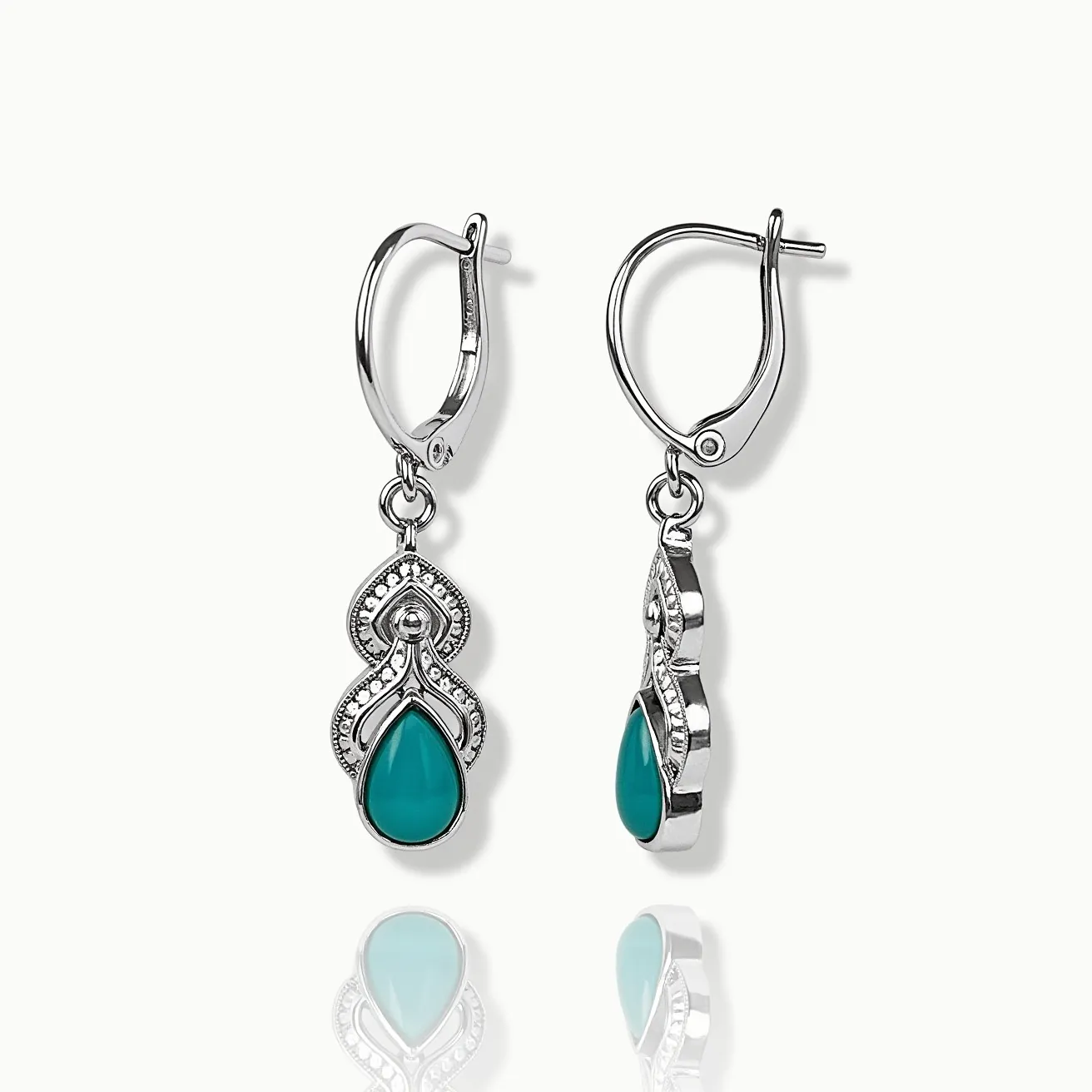 These teal earrings feature a striking teardrop-shaped teal gemstone set in an elegant silver-toned metal. The stones are cabochon cut, enhancing their smooth texture and deep color. These earrings are adorned with intricate metalwork that frames the gemstone with a series of decorative patterns, possibly accentuated by small, clear stones that add a subtle sparkle. The earrings are designed with lever-back clasps, offering secure and comfortable wear. The overall design highlights a graceful combination of classic and contemporary elements.