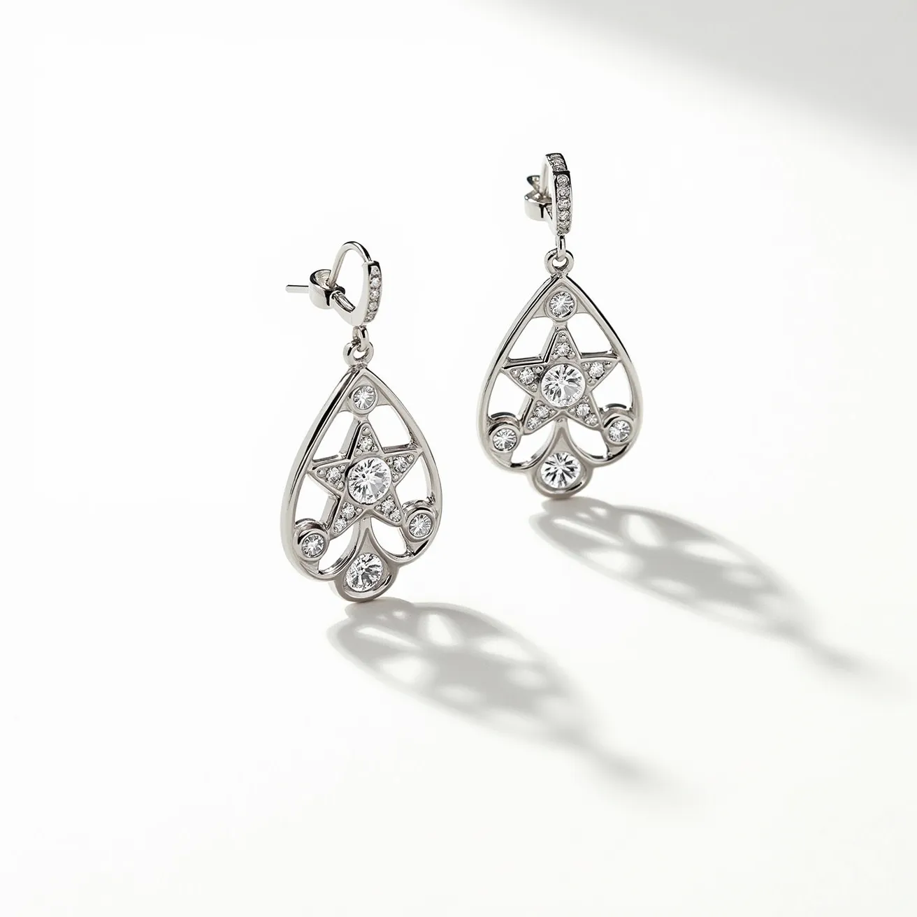 These teardrop earrings feature a delicate metal frame that forms an elegant teardrop silhouette, set with several clear, round cut gemstones. The stones are arranged in a sophisticated pattern with a central star design and are held securely in a bezel setting. The earrings are attached with a post and butterfly clutch back, providing a secure and comfortable fit. The polished finish adds a touch of luxury and enhances the overall sparkle and charm of the design.