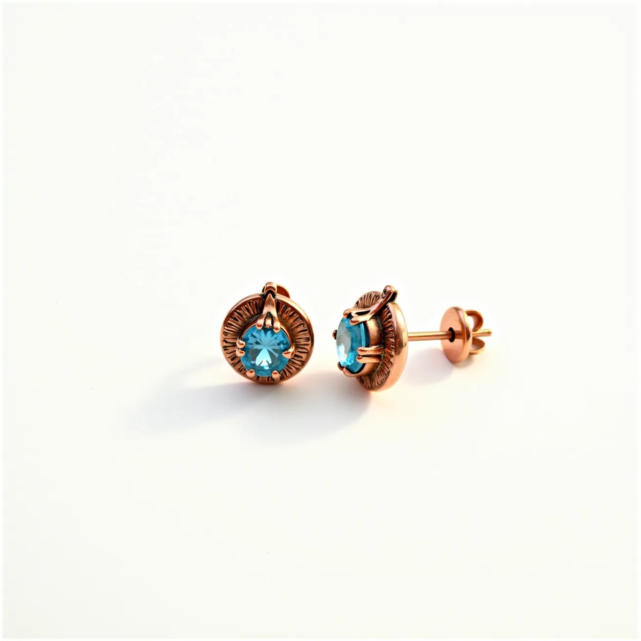 These thanksgiving earrings feature a central gemstone that appears to be a round-cut blue stone, set in a four-prong setting. The stone adds a vibrant touch of color to the earrings, contrasting beautifully against the warm tones of the metal. The base material of the earrings is a polished, copper-colored metal, which gives the piece a rustic, elegant appearance. The earrings are fastened with a secure butterfly clasp, ensuring they stay comfortably affixed to the ear when worn. The artistry and materials evoke a sense of subtle sophistication, making them a fitting accessory for a festive occasion.