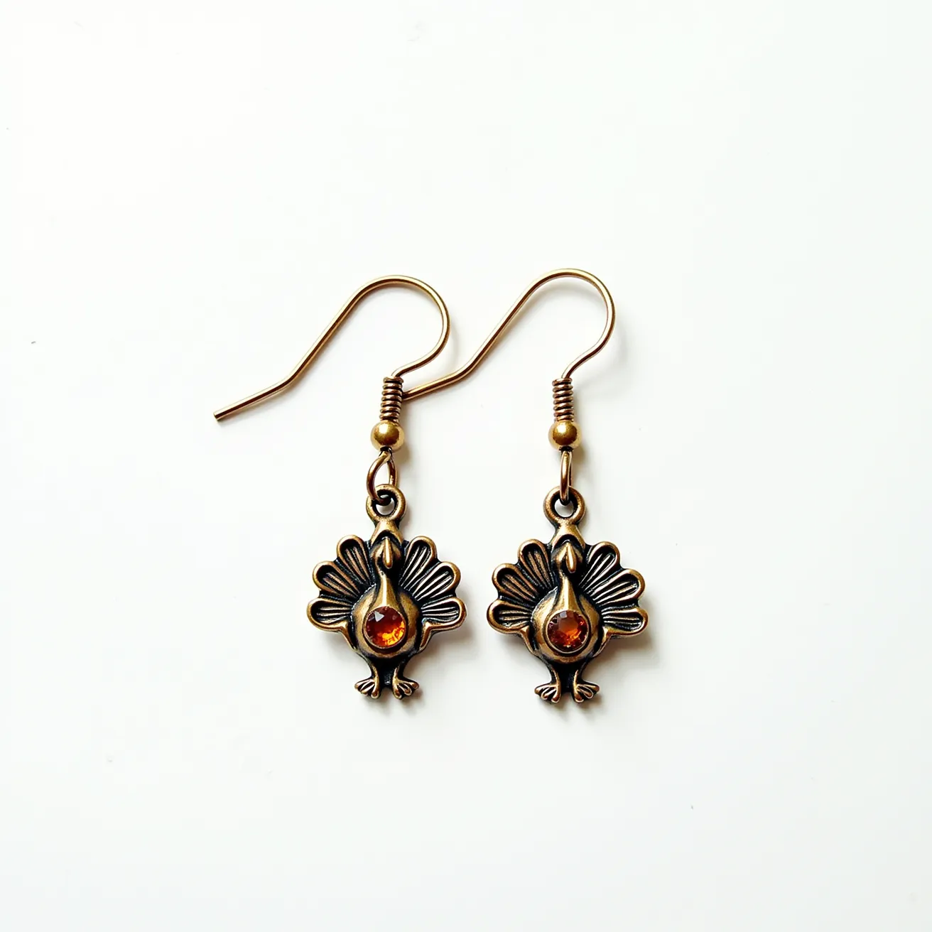 These thanksgiving earrings feature a charming turkey design crafted from a bronze-colored metal, giving them a rustic and festive appearance. The turkey motif is intricately detailed, showcasing a well-defined feather pattern. At the center of each turkey, there is a round amber-colored gem set in a bezel setting, adding a touch of sparkle and warmth to the design. The earrings are attached to simple wire hook clasps, which make them easy to wear and align with the overall vintage aesthetic. These earrings are perfect for adding a seasonal flair to any outfit.