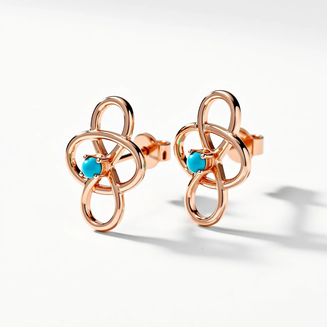 These turquoise stud earrings feature a captivating design that highlights a vibrant turquoise gemstone, beautifully rounded and secured in a prong setting. The main structure appears to be crafted from a gold-toned metal, which creates an elegant looped motif around the central stone, adding a touch of sophistication to the overall design. The posts are secured with traditional butterfly back clasps, ensuring ease of wear and security. The combination of the rich turquoise gem and the warm metal tone provides a striking contrast, making these earrings a stylish and eye-catching accessory.