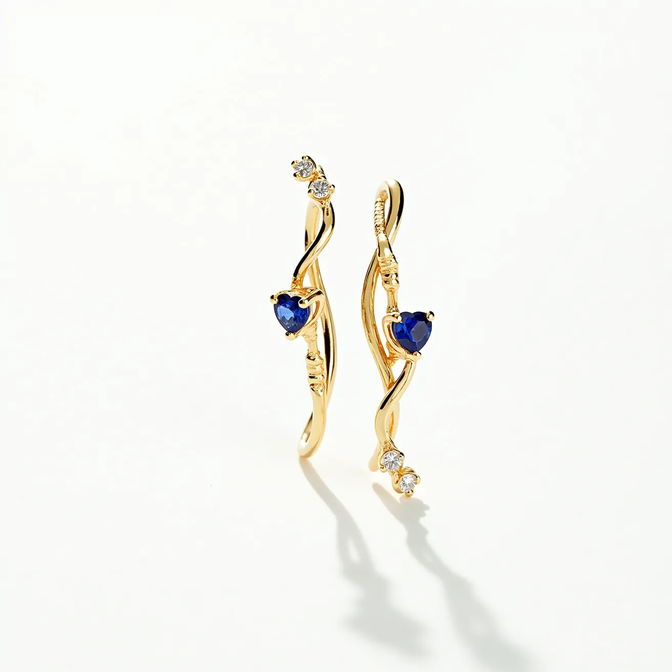 These twist earrings feature a sleek and elegant design crafted from a bright gold-toned metal, which gently twists to create a graceful and fluid shape. Each earring is adorned with a central heart-shaped blue gemstone, likely a sapphire, set securely into the gold to catch the light beautifully. Along the length of the twist, the earrings are also embellished with small round white gems, likely diamonds, adding extra sparkle and contrast. These smaller stones are set in a prong setting, and the earrings appear to use a hook or wire mechanism for easy and secure attachment to the earlobe.