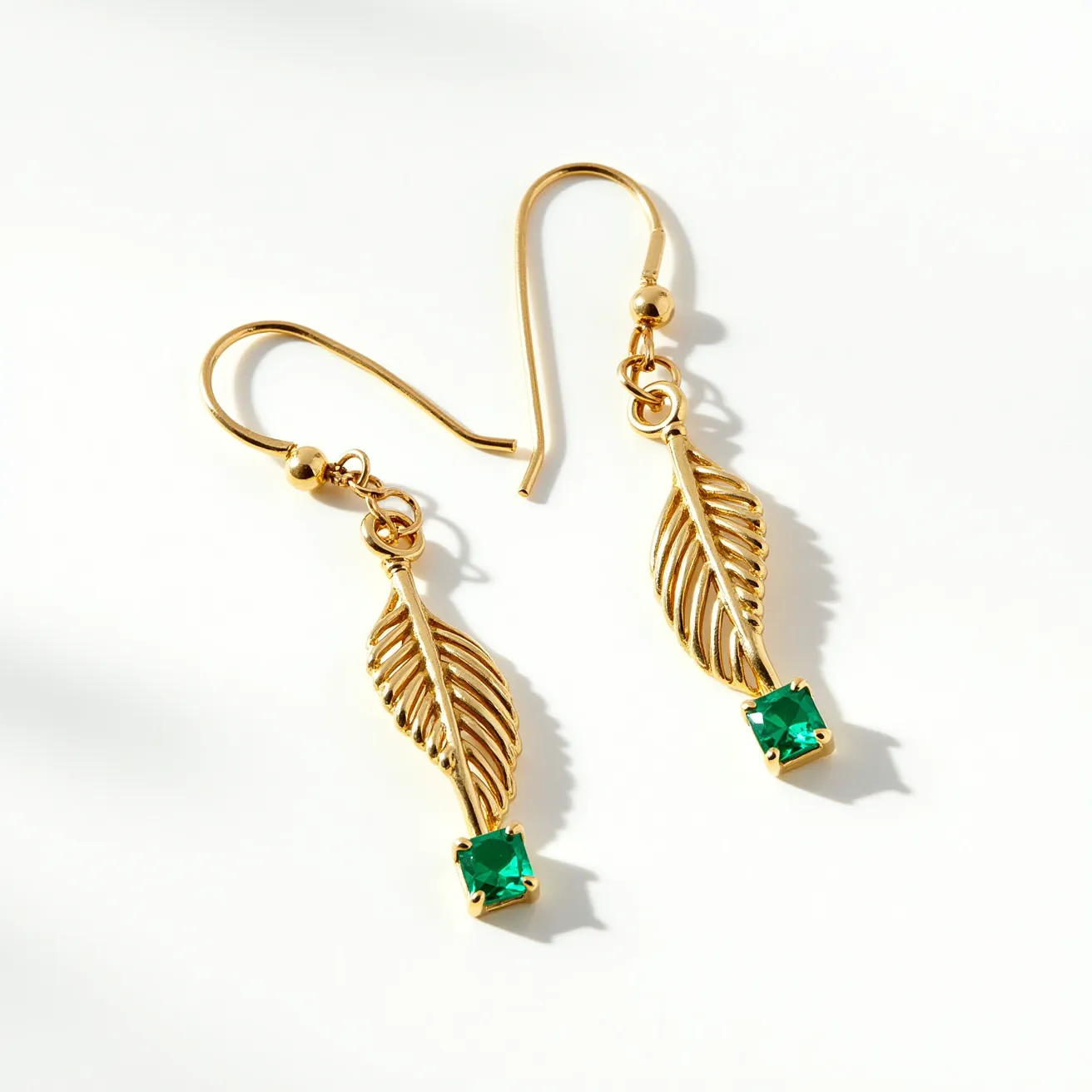 These twist earrings feature a delicate gold-toned metal design, forming an elegant leaf-like twist. Each earring is adorned with a vibrant green gemstone, cut in a square shape and set in a secure prong setting, adding a touch of color and sophistication. The earrings are equipped with a simple hook clasp, allowing for easy wear and removal. The overall design is both stylish and timeless, making them a versatile accessory for various occasions.