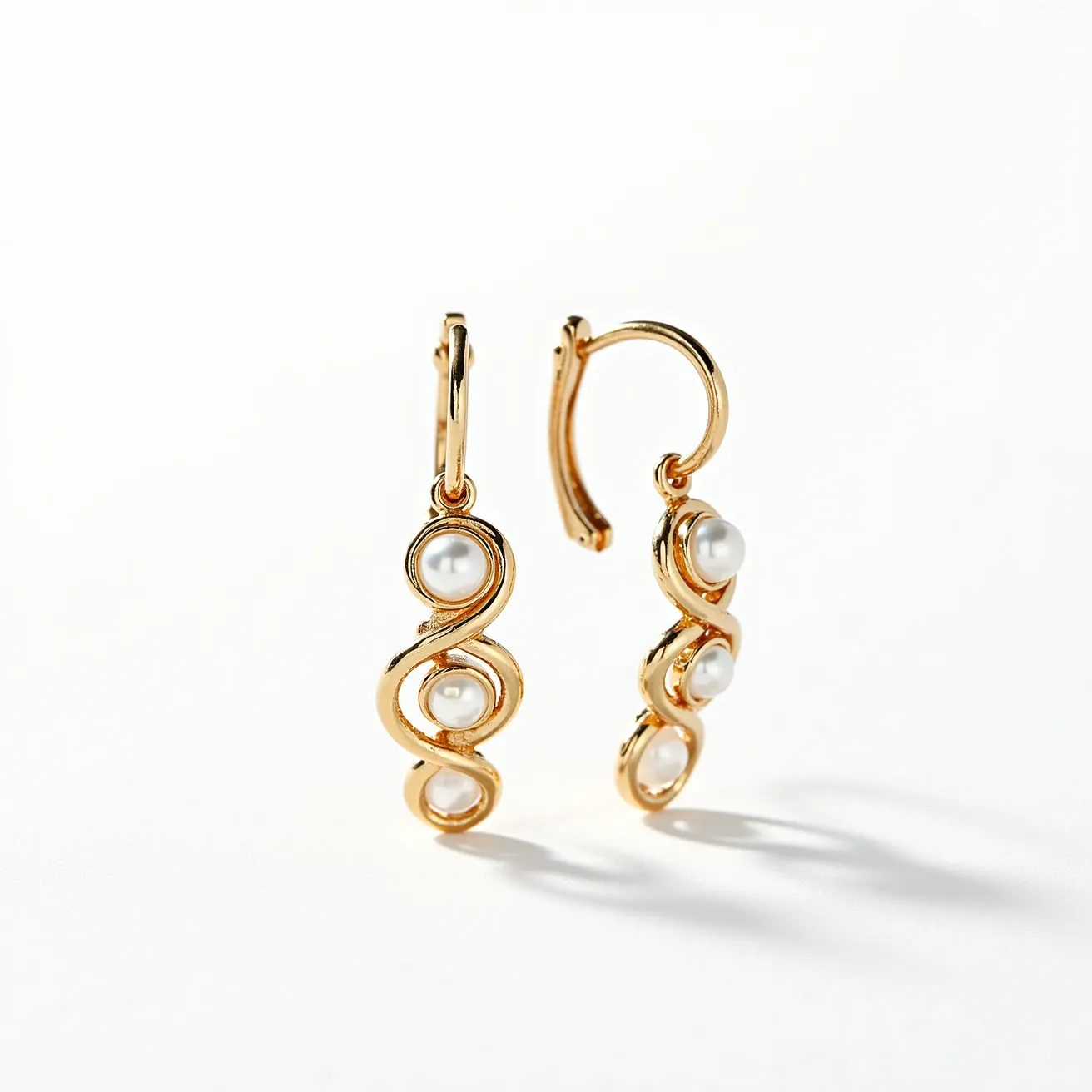 These twist earrings feature a graceful design with a gold-tone metal base that elegantly winds, resembling fluid curves. Nestled within the loops are three round, white pearls set in a bezel-style that adds a classic touch to the contemporary form. The earrings are secured with a hinged latch-back clasp, ensuring a comfortable and secure fit. The combination of the lustrous pearls and the warm gold finish creates a timeless and sophisticated accessory.