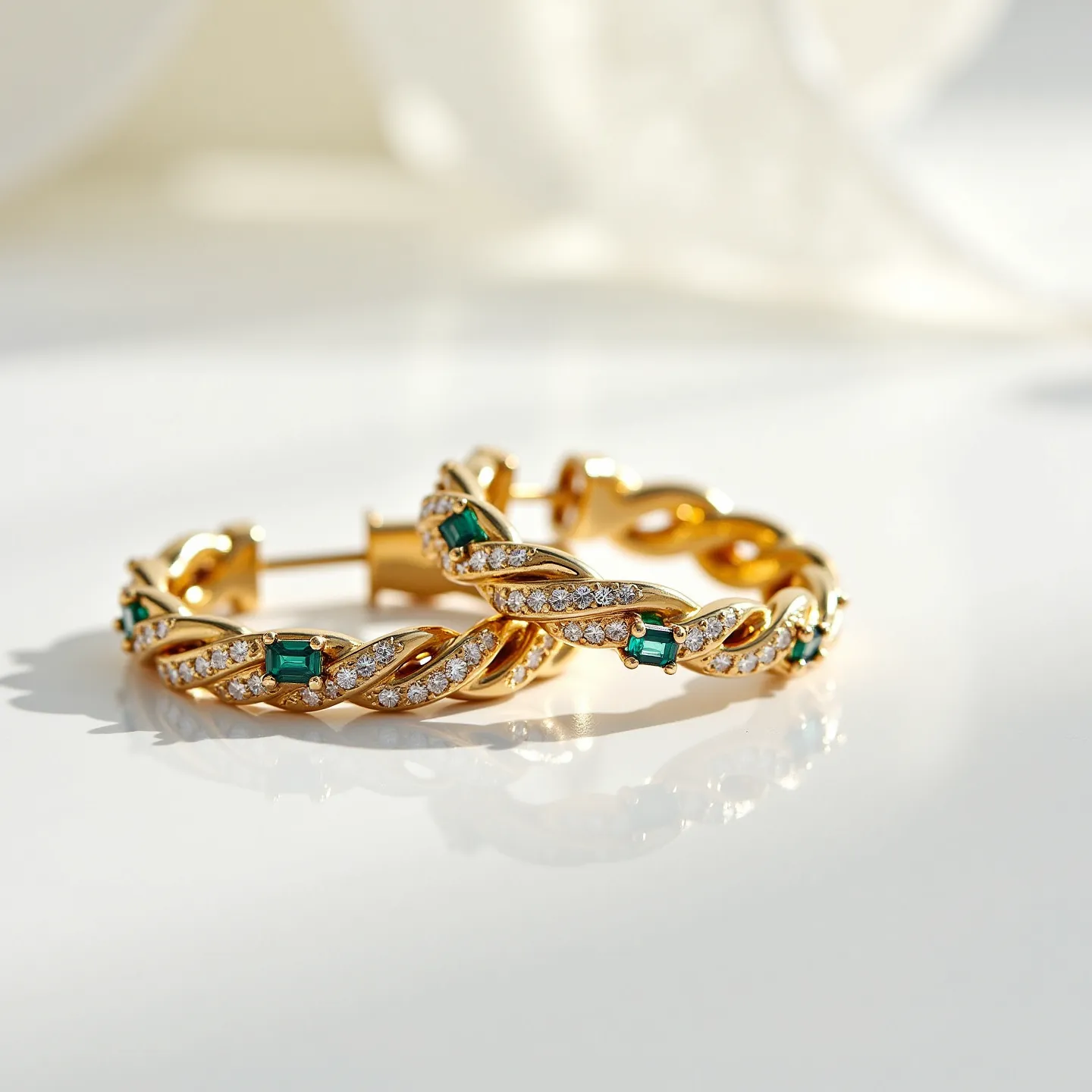 These twisted hoop earrings are crafted from a rich, gold-toned metal, featuring a sophisticated braid design that intertwines elegantly. The earrings are adorned with emerald-cut green gemstones, strategically placed at intervals along the hoops. Complementing the green stones are rows of small, round-cut clear gems, likely diamonds, set meticulously within the metal to enhance the sparkle. The earrings are designed with a post and latch back clasp, ensuring a secure and comfortable fit when worn. The combination of materials and the detailed craftsmanship give these earrings a luxurious and refined appearance.