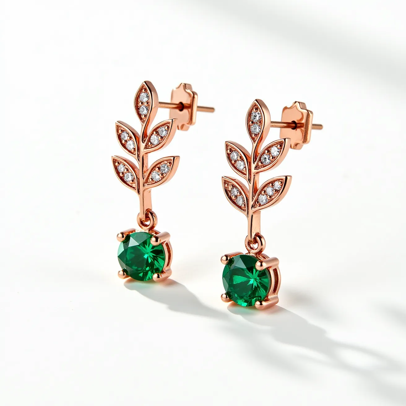 These valentines earrings feature a charming design with a rose gold finish, showcasing elegant leafy motifs adorned with small, round-cut clear gemstones set in a pavé style. The earrings culminate in a larger, round, forest green gemstone, likely a simulated emerald, held securely in a classic four-prong setting. The attachment style is a straightforward post with a butterfly clasp, ensuring a secure and comfortable fit. The combination of green and clear gemstones with rose gold creates a romantic and vibrant aesthetic, perfect for a Valentine's theme.