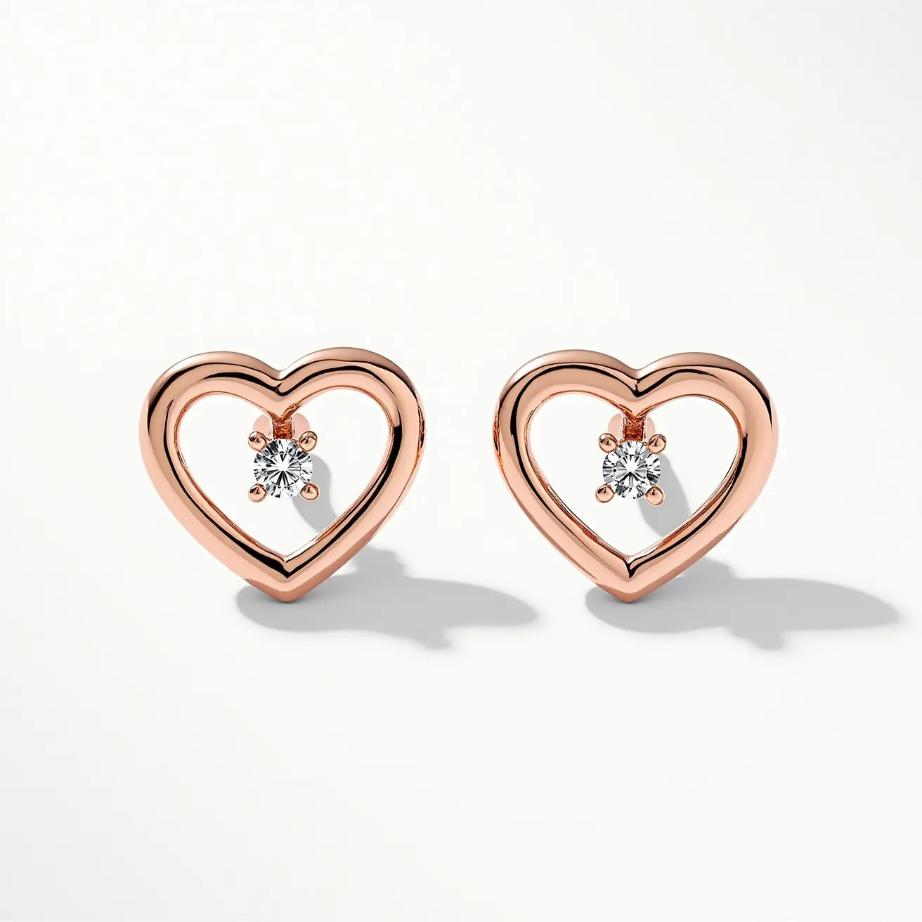 These valentines earrings feature heart-shaped frames crafted from a rose gold metal, exuding a warm and romantic aesthetic. Each earring showcases a brilliant round-cut gem, likely a diamond, centrally positioned within the heart. The gems are securely held using a four-prong setting, which highlights their sparkle and clarity. These earrings are designed as studs, with posts that allow for secure and comfortable wear. The combination of the gleaming metal and the sparkling gems makes these earrings a perfect accessory for a romantic occasion.