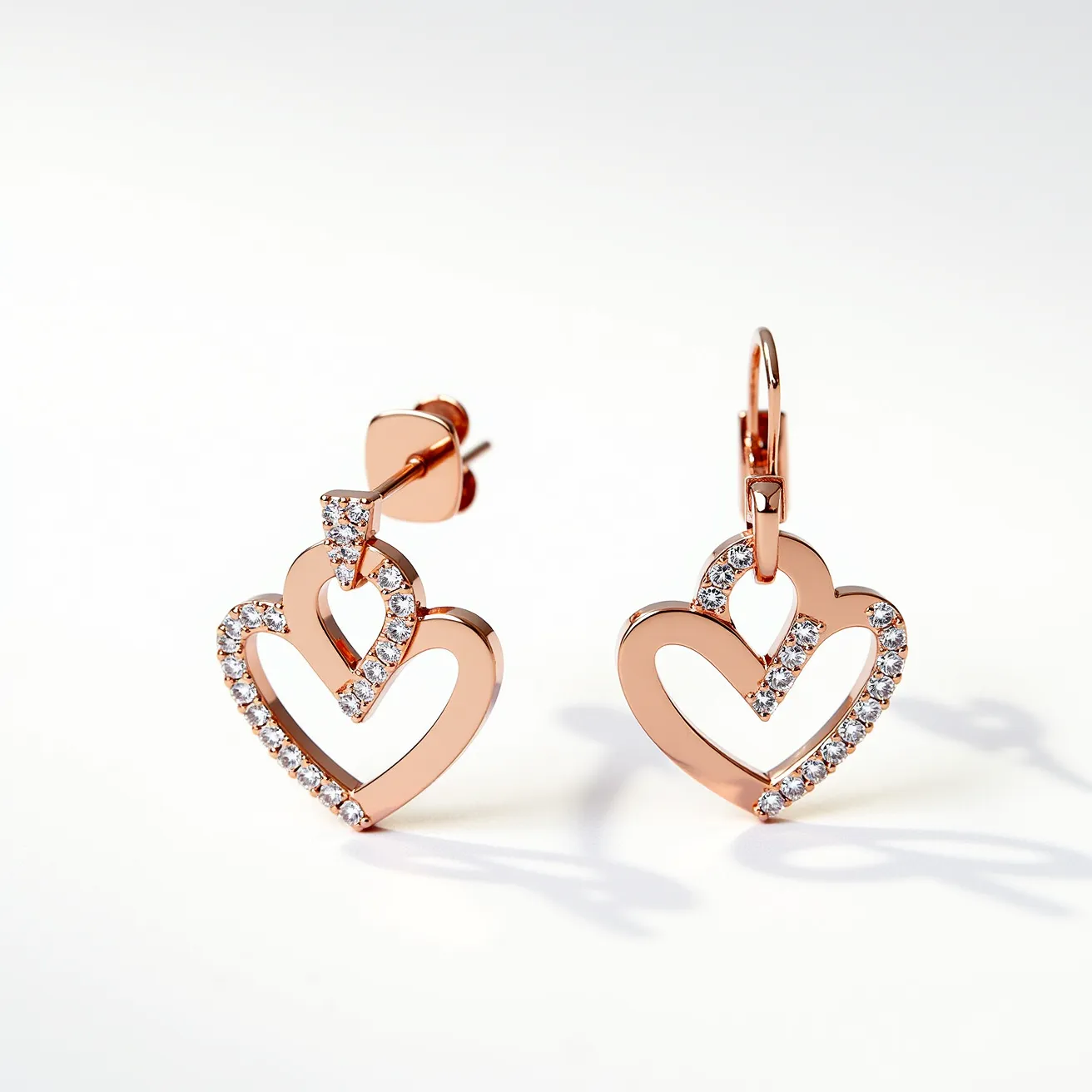 These valentines earrings feature a charming double heart design crafted from rose gold, enhancing their romantic appeal. Each heart is delicately adorned with small, round-cut cubic zirconia stones set in a pavé style, adding a touch of sparkle and elegance to the overall composition. The earrings have two different attachments: one earring utilizes a classic stud post with a butterfly back for secure fastening, while the other uses a lever-back clasp, allowing for comfortable wear. These elements combine to create a visually engaging piece, perfect for conveying love and affection.