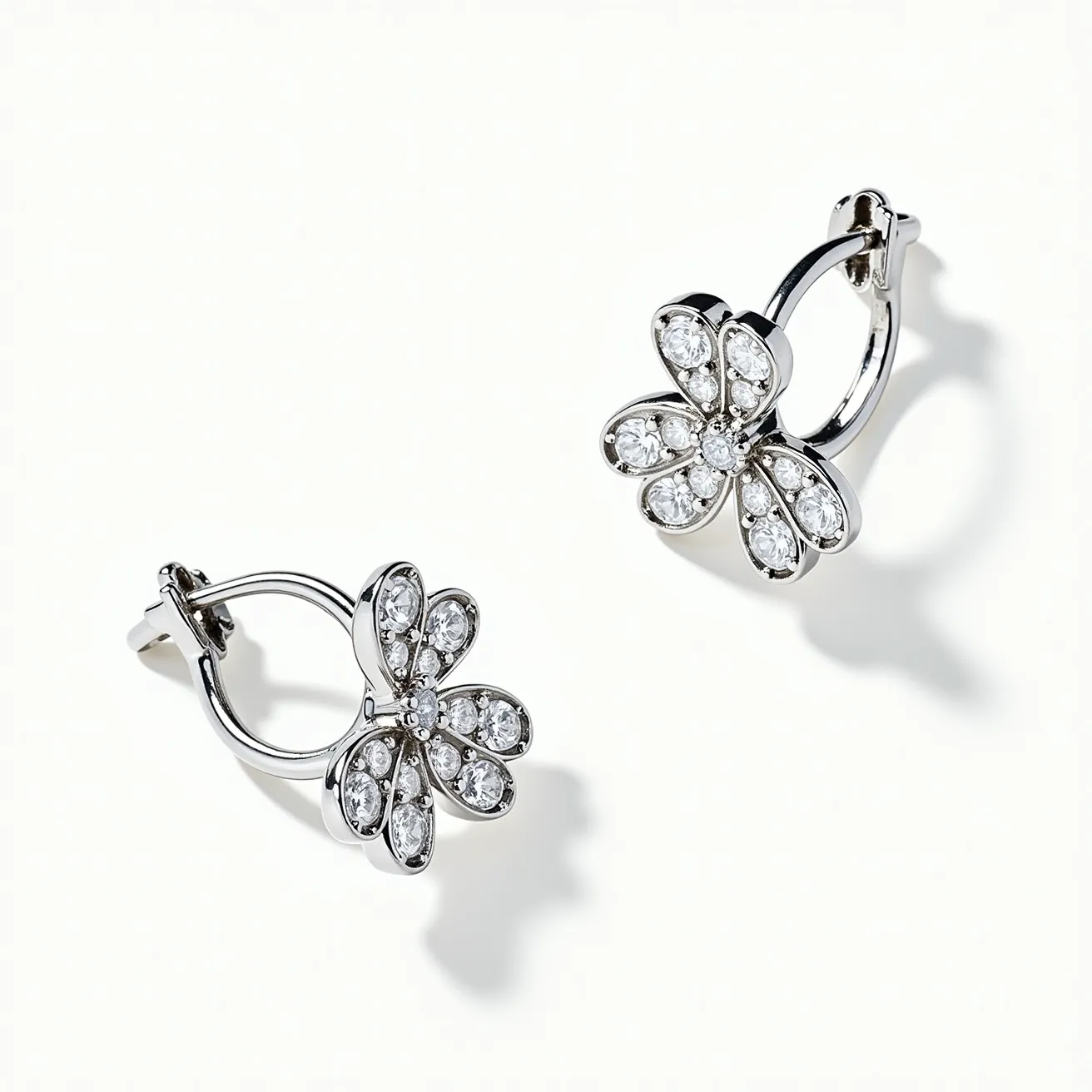 These white earrings feature a floral design crafted in a silver-toned metal, possibly sterling silver. The petals of each flower are adorned with clear, round-cut stones, likely diamonds or cubic zirconia, set in a pavé style to maximize their sparkle and enhance the intricate design. The earrings utilize a lever-back clasp, ensuring they remain secure when worn. The overall appearance is elegant and sophisticated, making them suitable for both casual and formal occasions.