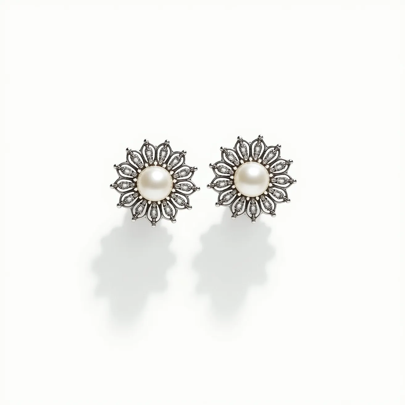 These white gold earrings feature a central round pearl as the main gemstone, surrounded by a floral design crafted in white gold. Each petal encases small, clear stones, likely diamonds, set in a pavé style to enhance the brilliance of the design. The earrings utilize a stud attachment, providing a secure and elegant fit. The combination of pearls and diamonds against the white gold creates a classic and sophisticated look.