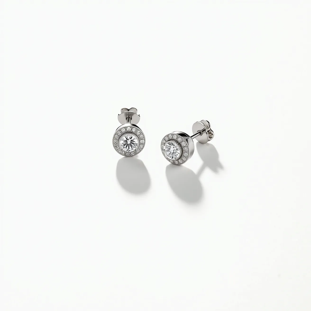 These white sapphire earrings feature a central round-cut gemstone set in a classic bezel style, bordered by a halo of smaller stones, which enhances their brilliance and elegance. The earrings are crafted from a lustrous metal, likely white gold or platinum, providing a sophisticated and polished finish. They are designed with a secure post and butterfly back clasp, ensuring stability and comfort when worn. The settings and materials highlight the translucent beauty of the white sapphires, making them a stunning accessory for any occasion.