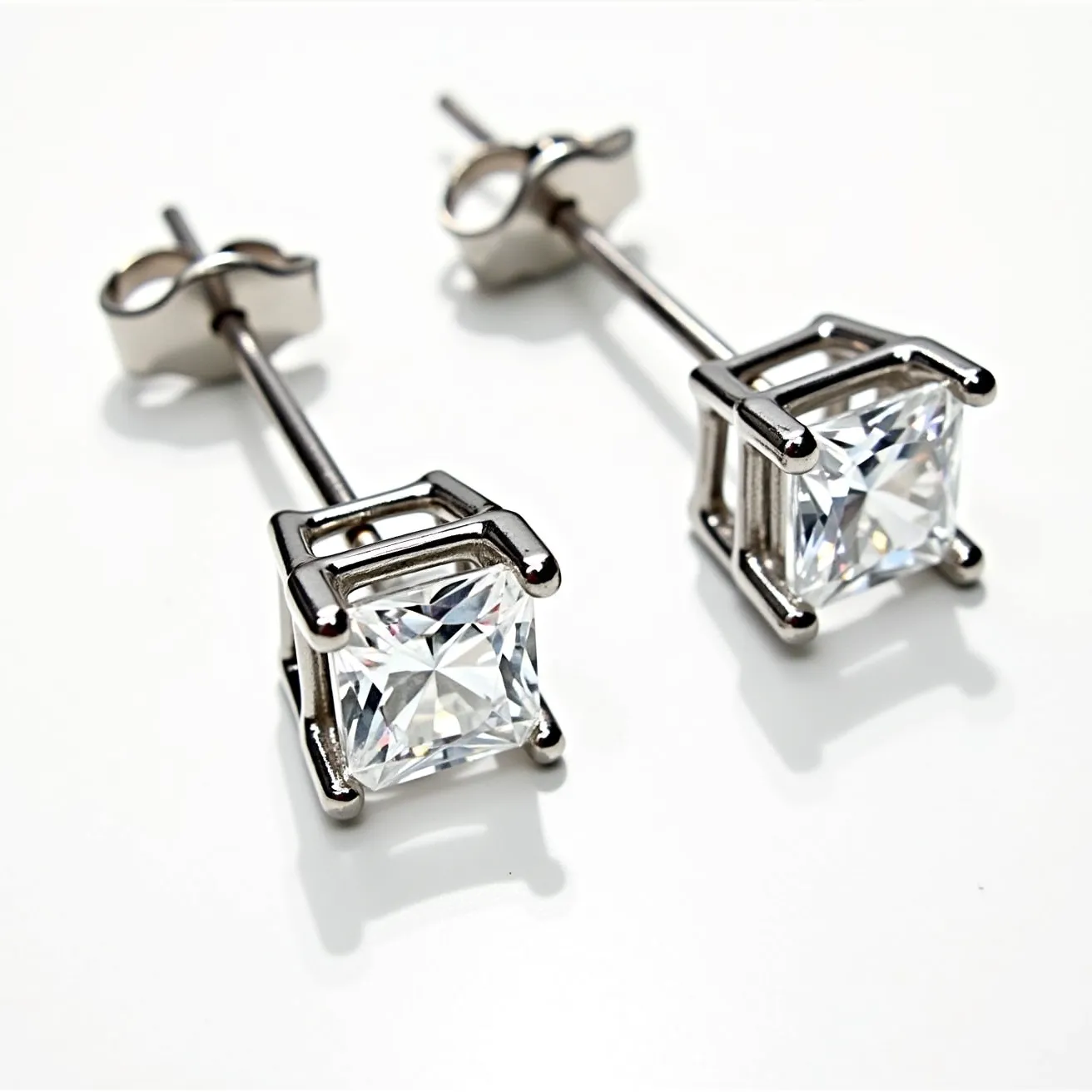 These white sapphire earrings feature square-cut white sapphires elegantly set in a modern prong setting. The setting is crafted from a sleek, polished metal, possibly white gold or platinum, which complements the brilliance of the gemstones. Each earring is secured with a classic post-back design, featuring butterfly clasps that ensure comfort and security when worn. The overall design is both timeless and versatile, making these earrings suitable for a variety of occasions.