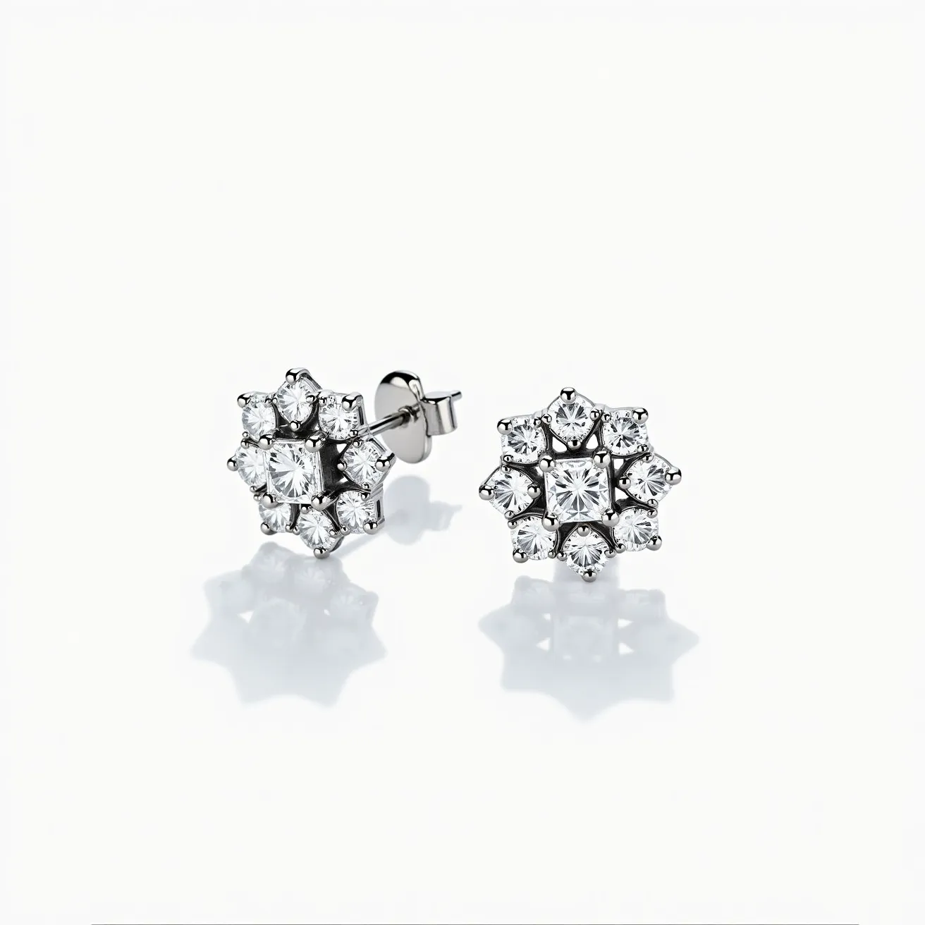 These white sapphire earrings feature a sophisticated arrangement of gemstones, with each earring showcasing a central square-cut white sapphire surrounded by multiple smaller round-cut white sapphires, all set in a metal framework that appears to be made from a shiny white gold or platinum. The earrings have a floral or starburst design, which adds an element of timeless elegance. They are fitted with a classic post and butterfly clutch back, offering secure attachment while enhancing the overall refined look. The intricate setting of the stones highlights the brilliance and clarity of the white sapphires, making these earrings an exquisite accessory for any occasion.