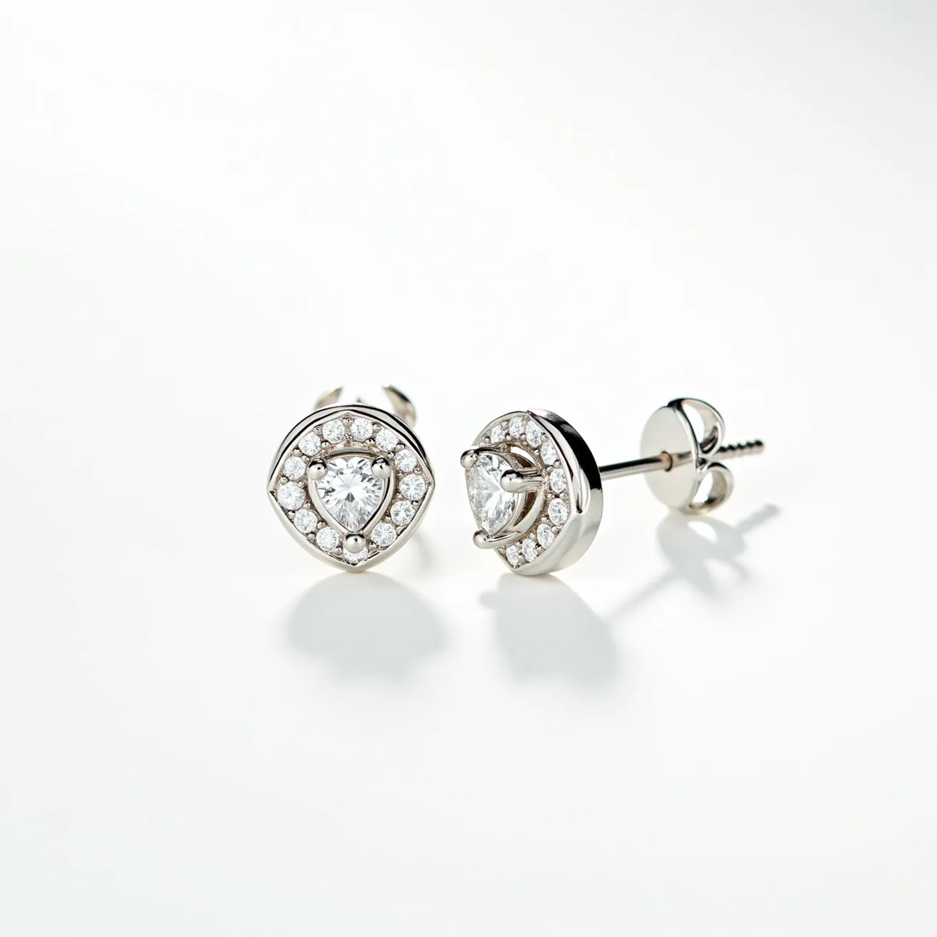 These white sapphire earrings feature a central heart-shaped white sapphire gem, expertly cut to enhance its brilliance and clarity. They are set in a polished metal, likely white gold or platinum, combining durability with elegance. Encircling the central gemstone, there's a halo of smaller round white sapphires, meticulously arranged to amplify the earrings' sparkle. The setting is secure and highlights each stone's natural shine. These earrings use a screw back clasp, ensuring a snug and secure fit.