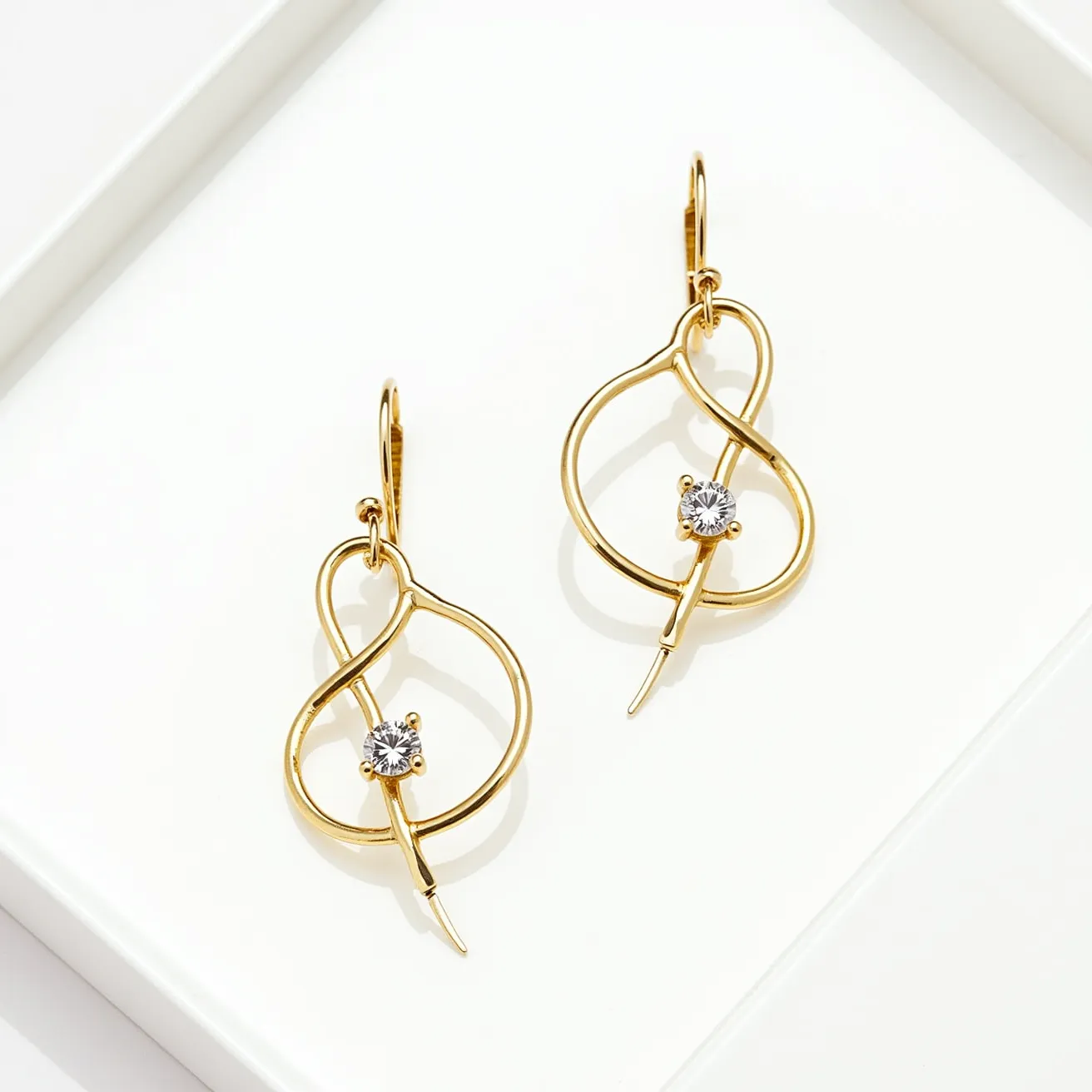 These wire earrings feature an elegant design crafted from gold-toned wire, forming a fluid, looped structure. The centerpiece includes a round-cut gem, likely a diamond or a clear crystal, which is prong-set, adding a touch of sparkle. The earrings are designed with a simple hook attachment, allowing them to dangle gracefully when worn. The overall aesthetic is both modern and sophisticated, suitable for various occasions.