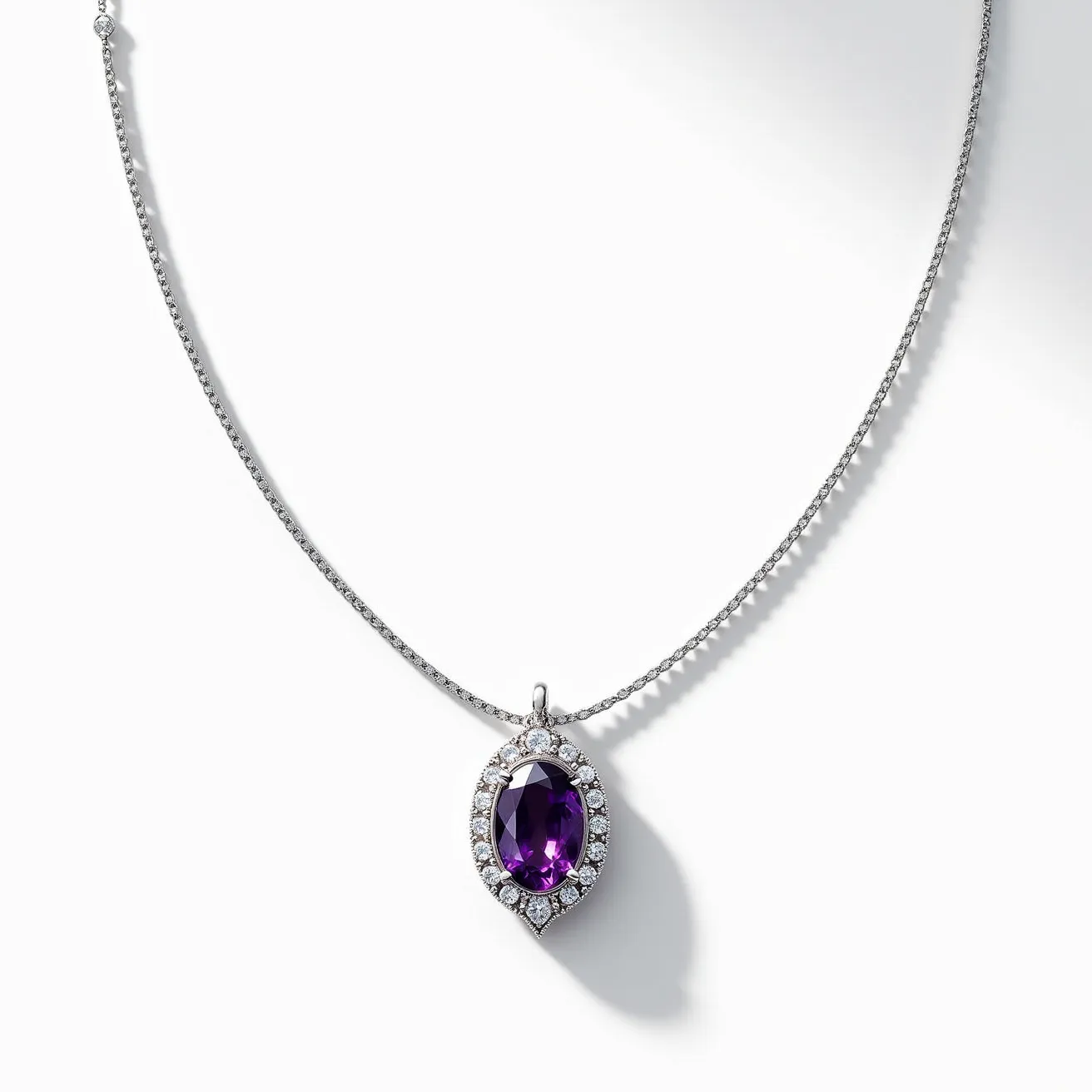 This alexandrite necklace features a stunning oval-cut alexandrite gemstone as the centerpiece, set in a halo of small, round brilliant-cut diamonds. The alexandrite displays a deep, rich hue with a vibrant sheen, showcasing its unique color-changing properties. The halo setting enhances the central gem's allure, providing a sparkling contrast to the deep color of the alexandrite. The necklace is likely crafted from a high-quality white metal, possibly white gold or platinum, designed to complement the cool tones of the stones. A delicate chain completes the piece, securing with a simple yet elegant clasp.