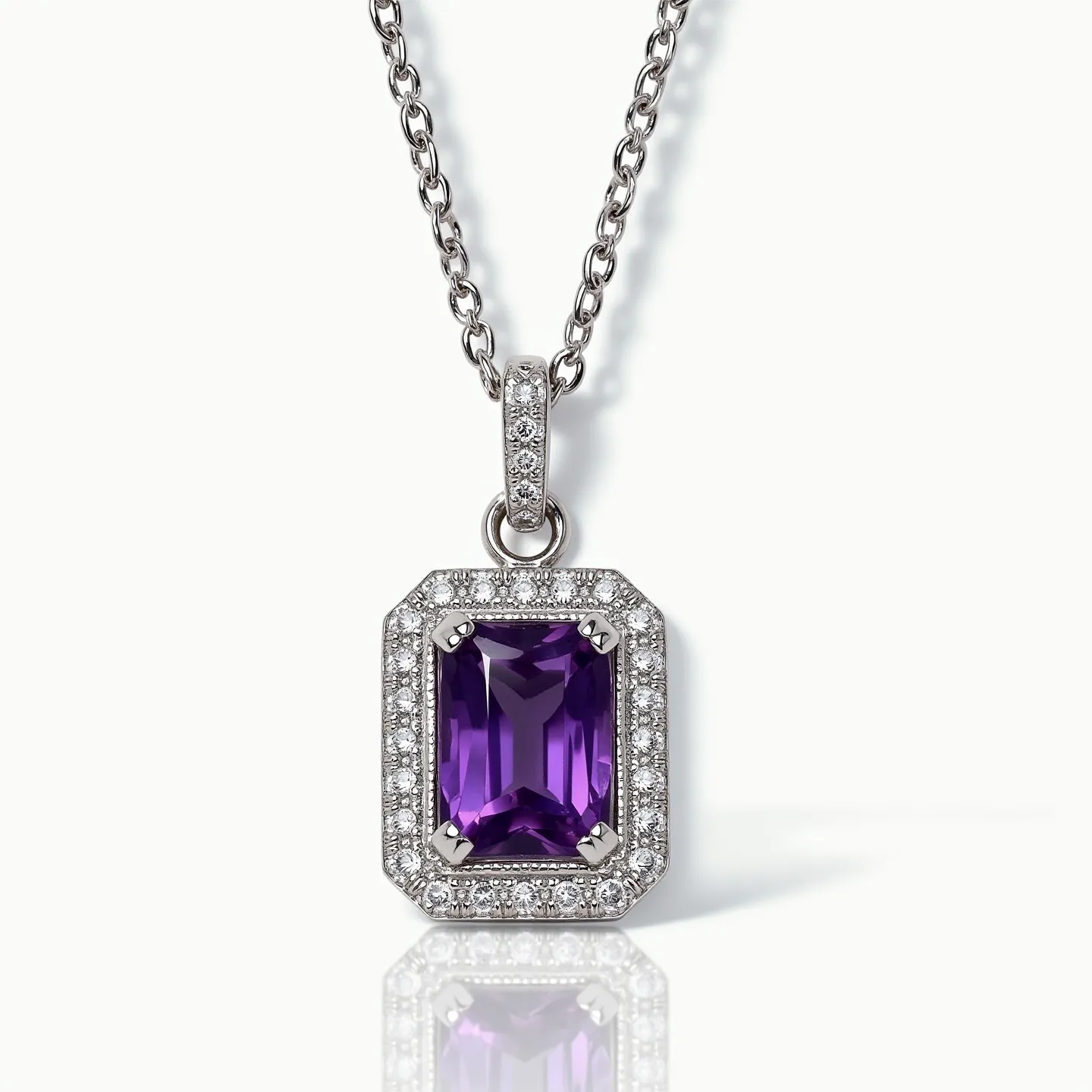 This amethyst necklace features a prominent rectangular-cut amethyst set in a gleaming silvery setting. Surrounding the vibrant purple stone is a halo of small, sparkling white gemstones, likely diamonds, which enhance its brilliance. The pendant is attached to a delicate, intertwined chain, possibly made of white gold or platinum, adding elegance to the design. The clasp is not visible, but the overall craftsmanship suggests a secure, high-quality attachment suitable for such a refined piece.